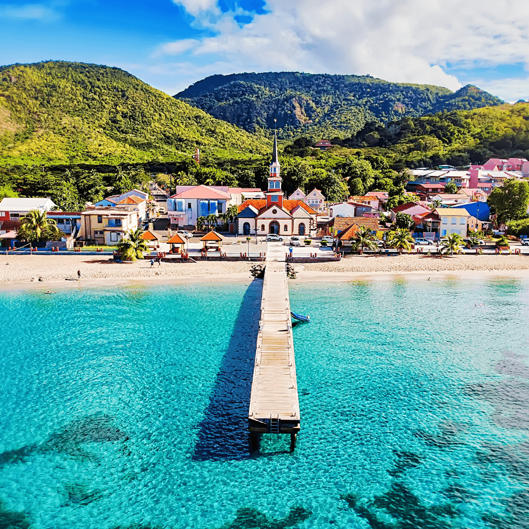Ponton menant vers un village côtier entouré de collines verdoyantes et d’une mer turquoise, en Martinique