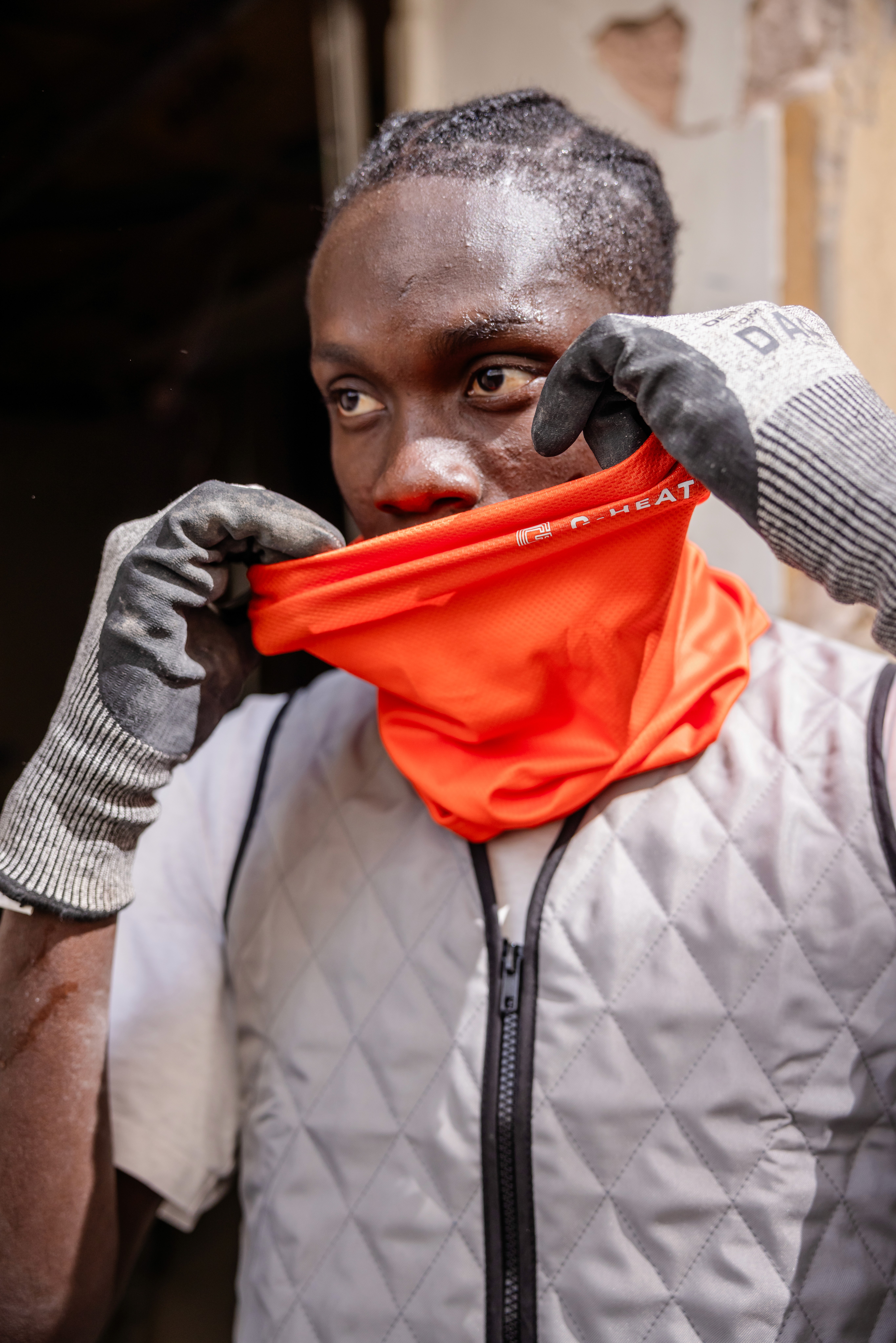 Construction worker wearing an orange G-Heat cooling neck gaiter on his face