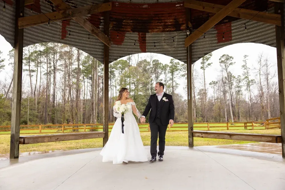 Bride and groom holding hands under a wooden pavilion