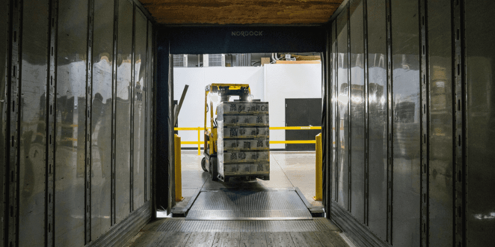 A forklift loading pallets into a truck at a loading dock