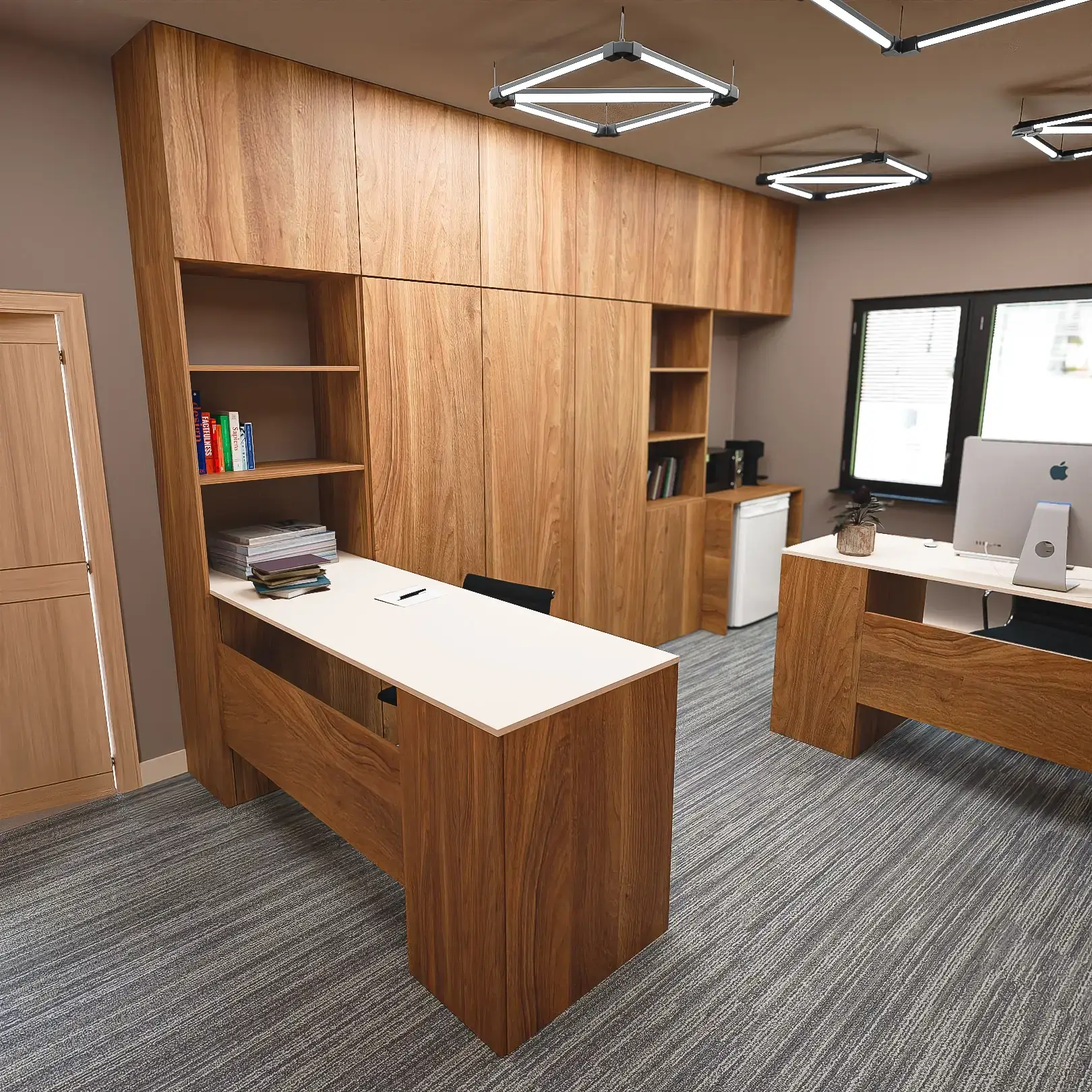 Stanowisko pracy w biurze: biurko z nadstawką w kolorze drewna oraz profesjonalne fotele biurowe.