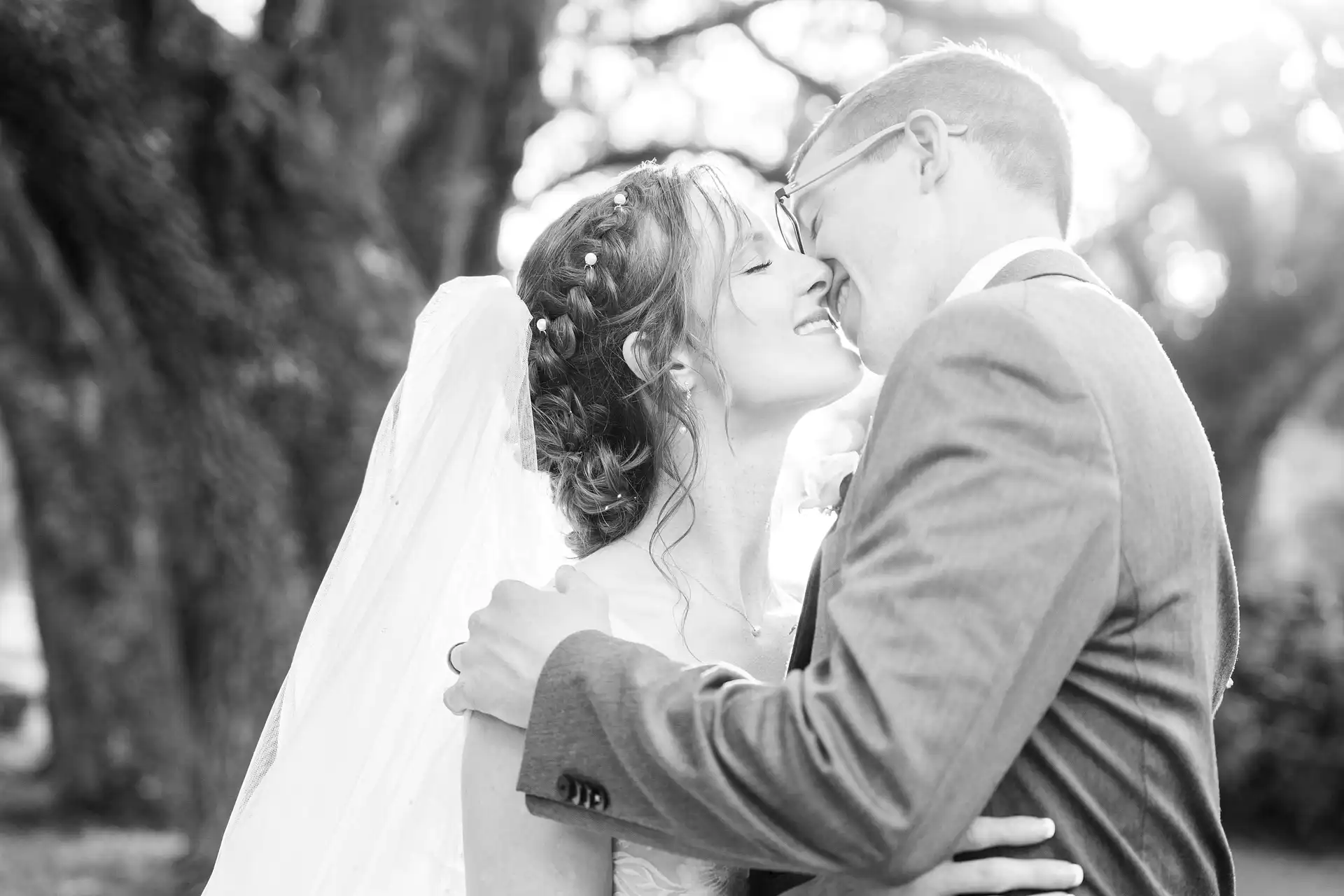  a wedding couple gently embracing each other with their eyes closed going in for a kiss
