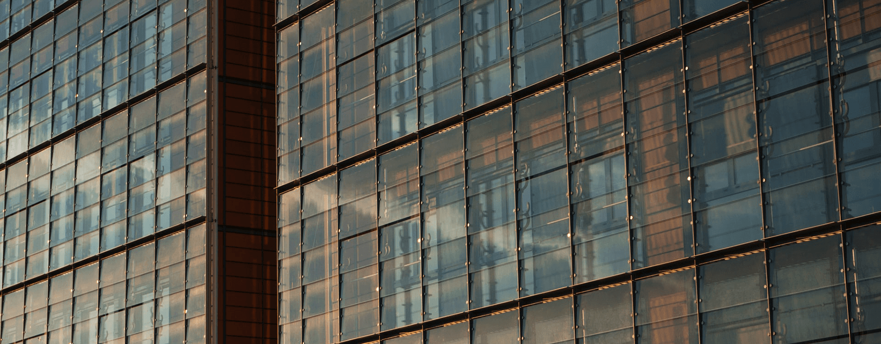 Close-up of large glass windows reflecting clouds and light, framed by wooden structures.