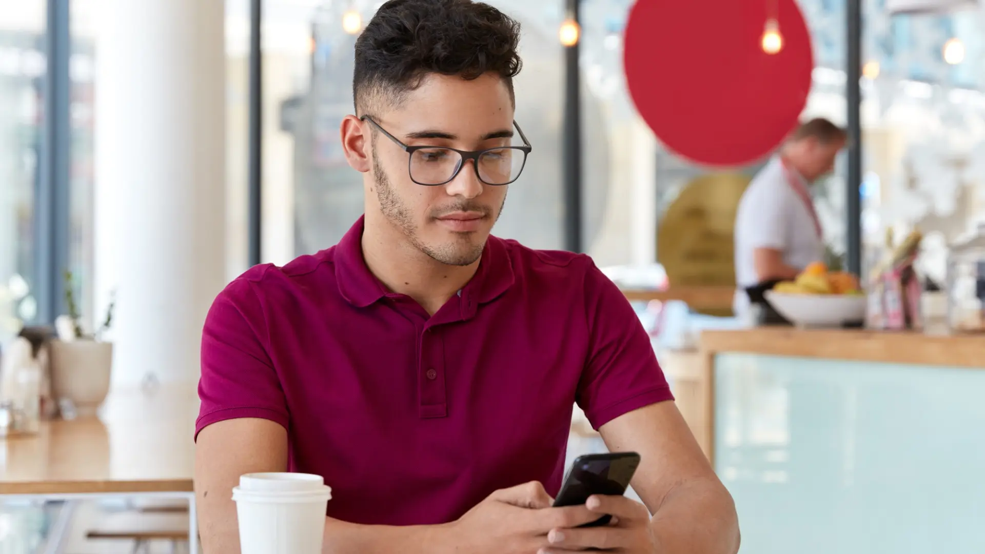 A young professional in a cafe scrolls through tiktok on his smartphone, researching job search tips and trends.