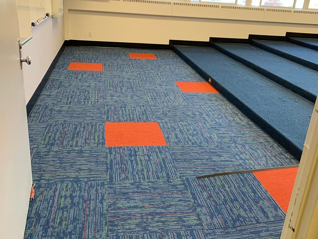 Finished blue carpet tile floor and risers with orange inserts in a conference room