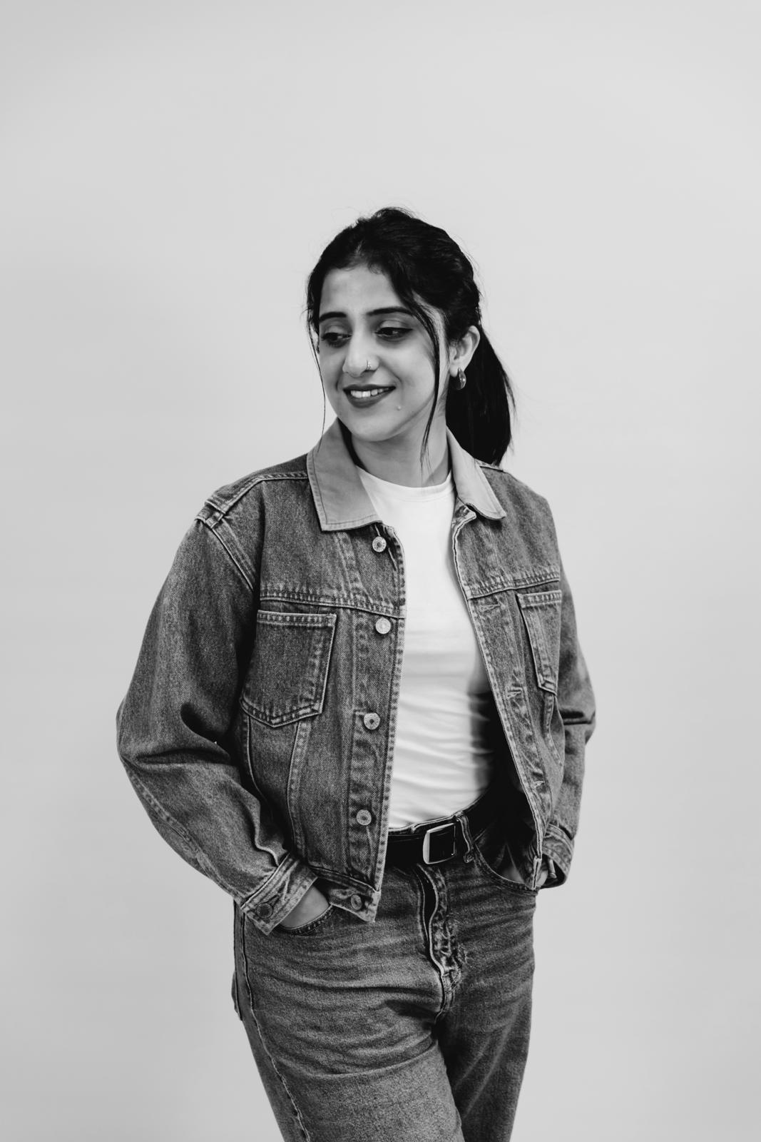A thoughtful young person with dark hair gazes to the side, captured in soft black and white lighting.