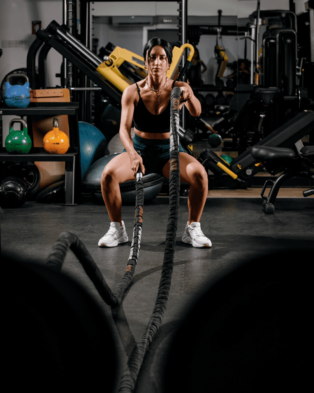 A man with headphones flexing in front of a mirror with red gym equipment behind him. Quote: “These workouts aren’t just effective – they’re empowering…” – Freelance Photographer.
