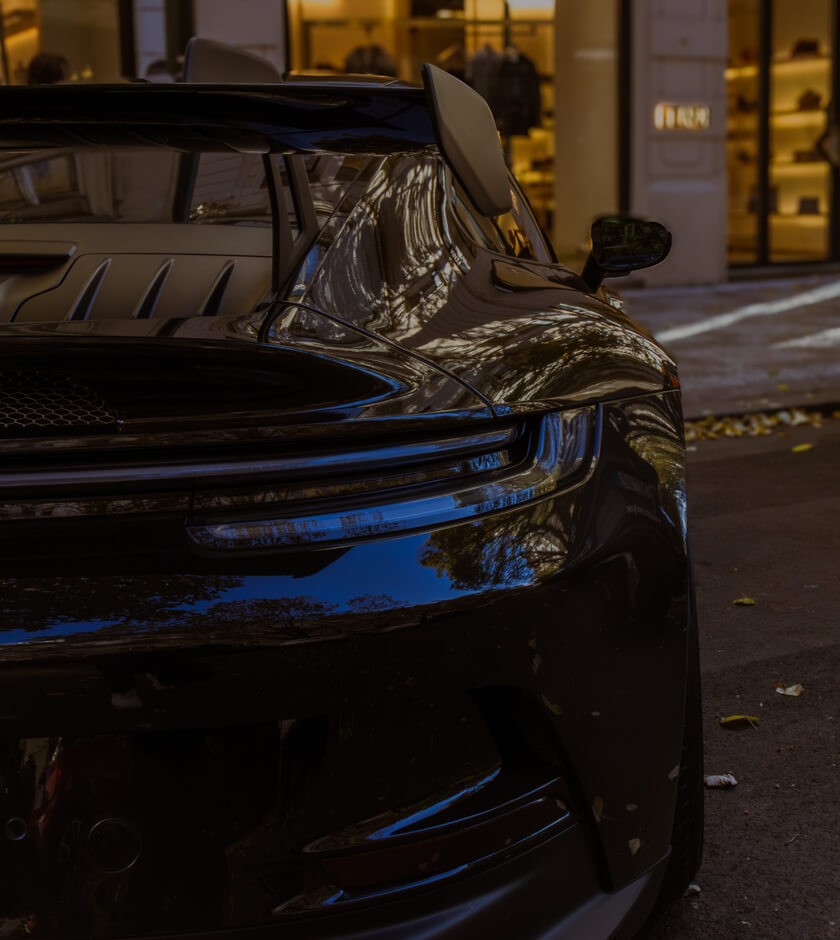 Detail zadního křídla a světel černého vozu Porsche