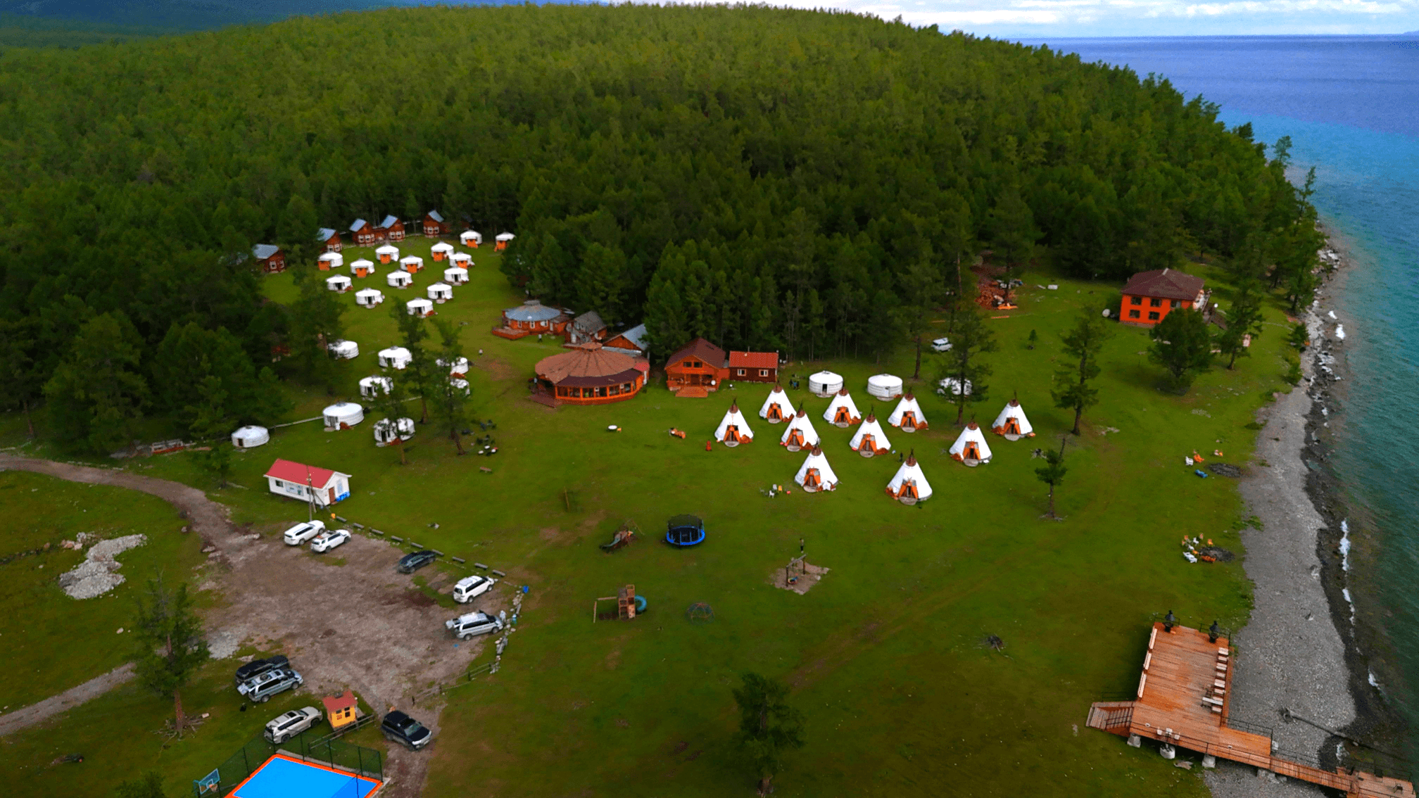 Smiling young woman with long hair standing against a dark green background, holding a finger to her chin.