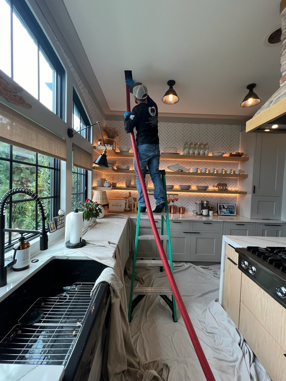 Technician cleaning a ceiling vent with a rotary brush pole
