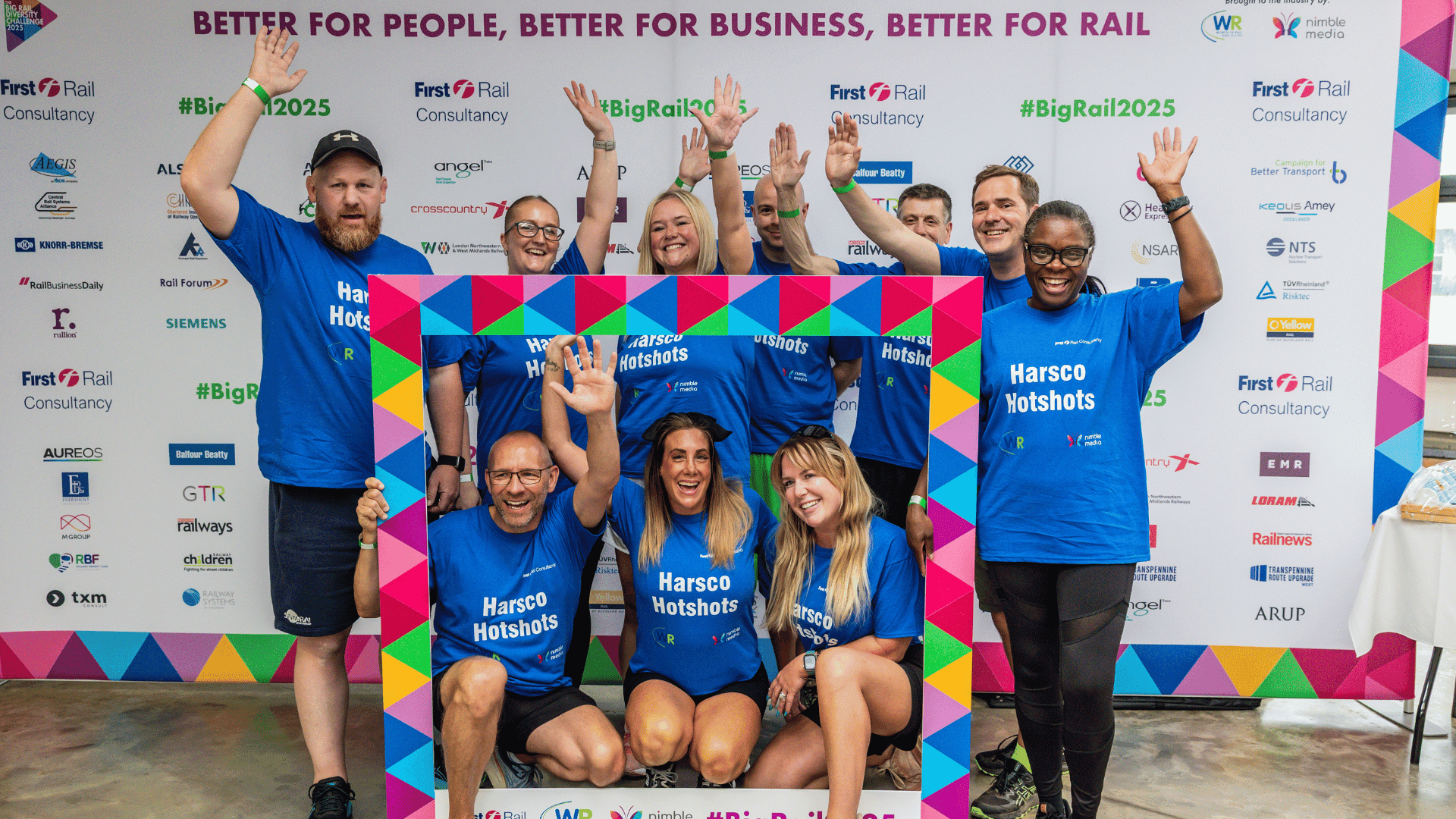 Outdoor team-building event with participants wearing matching blue shirts, taking part in inflatable obstacle courses and games, smiling and cheering, with the words 'ENTER A TEAM' in large bold white and green text across the image.
