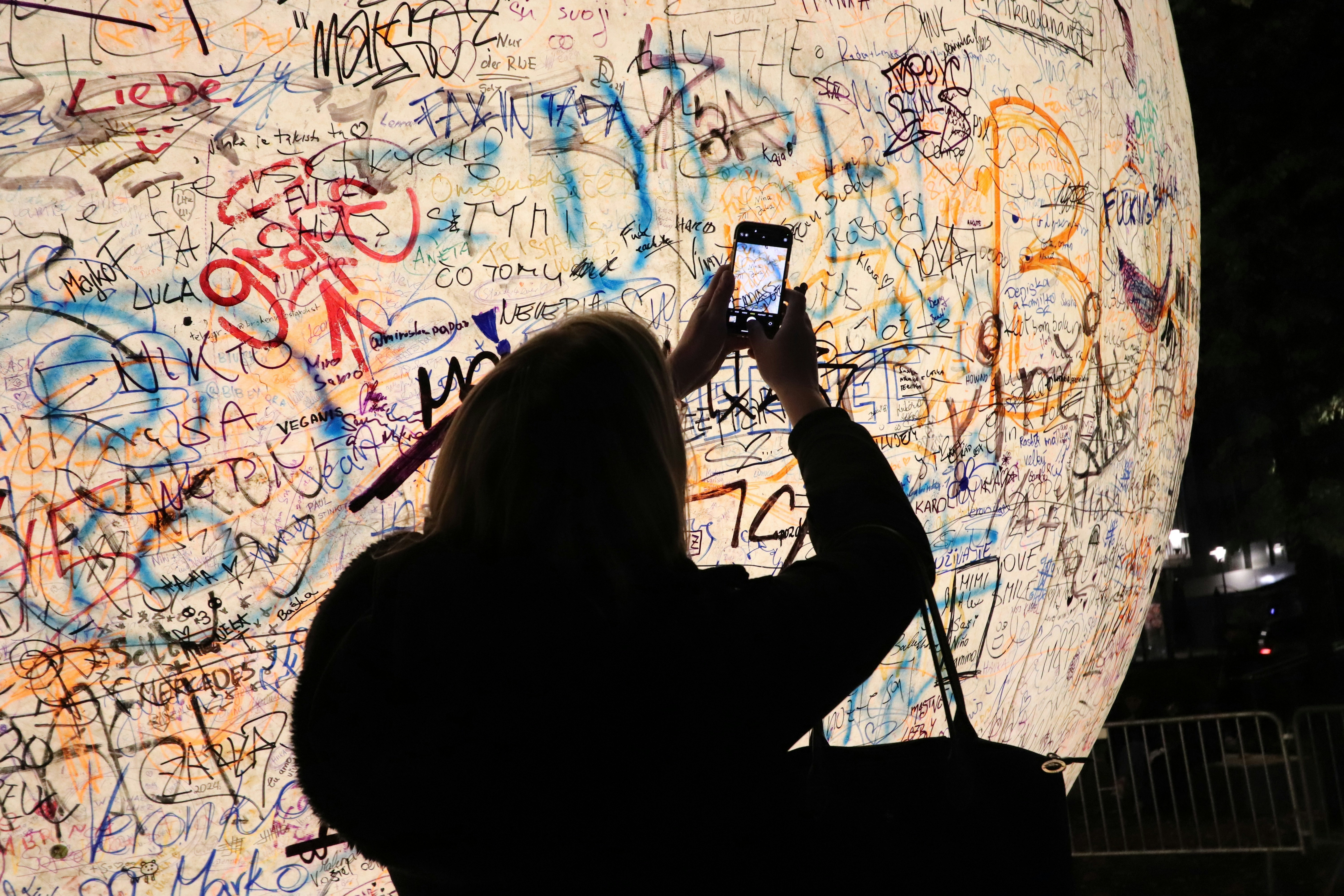 A person taking a picture of graffiti on a wall