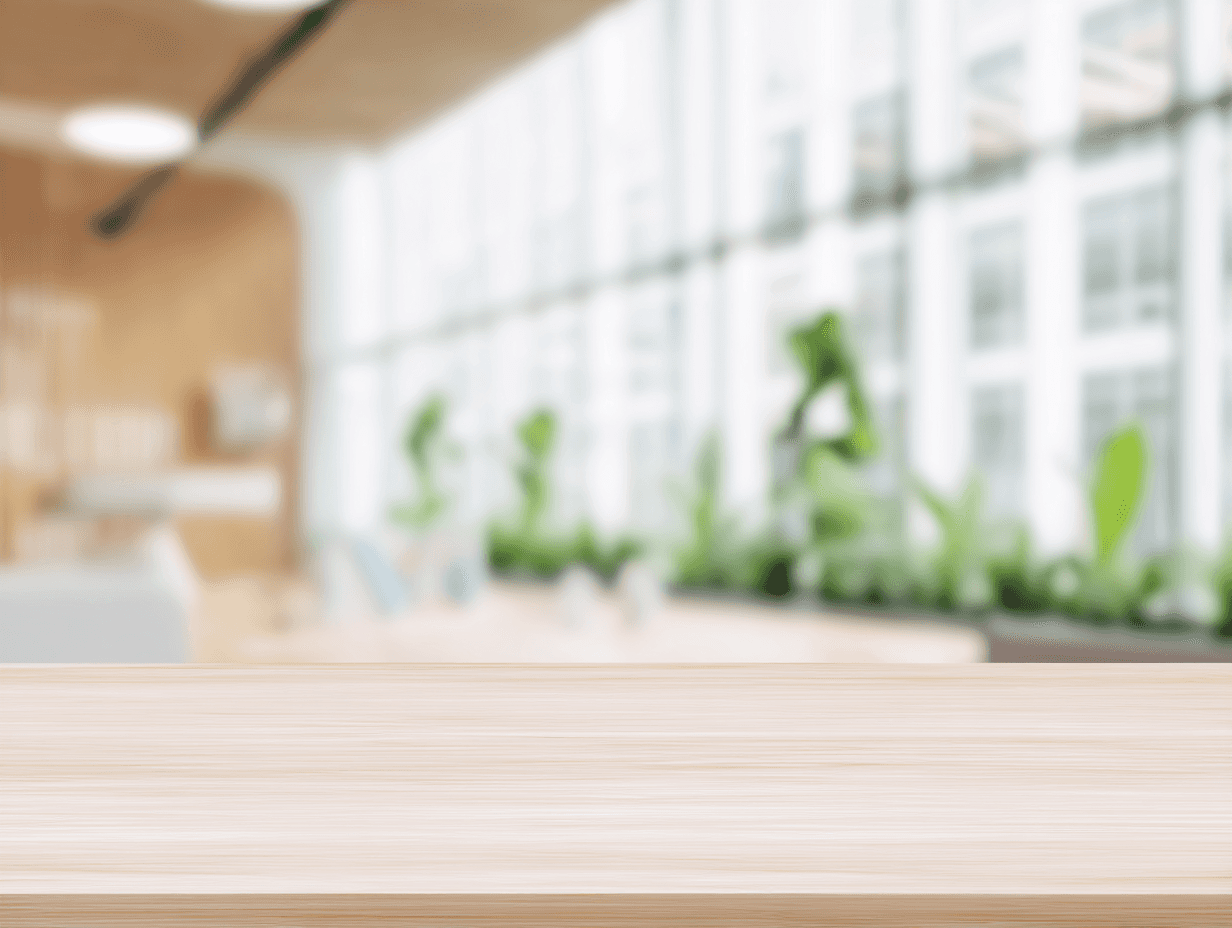 Blurred image of a modern office with large windows, light wood surfaces, and potted plants, creating a soft, bright, and airy atmosphere.