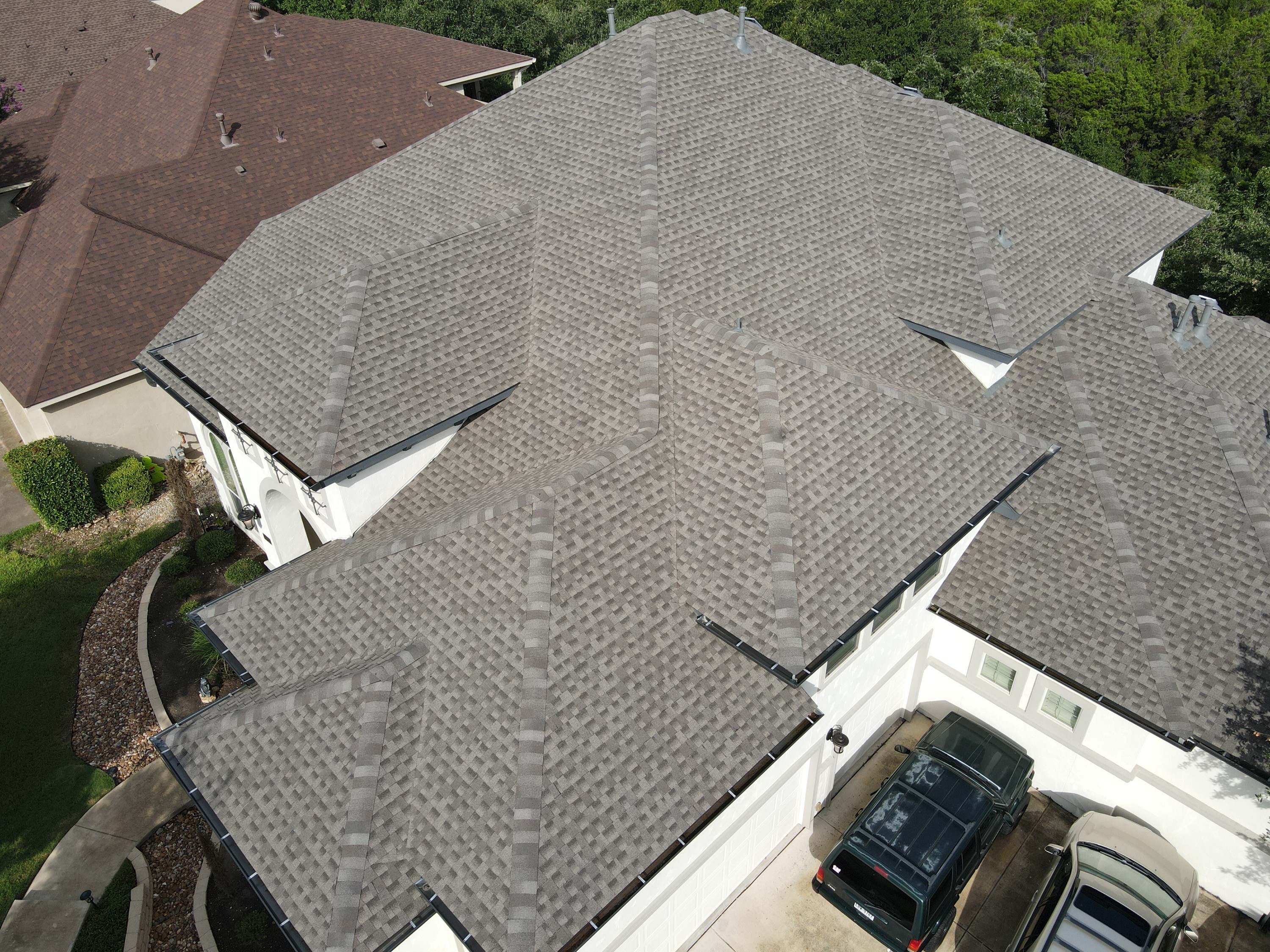 Drone view of a gray architectural shingle roof with intersecting hips and ridges; manufacturer not verified.