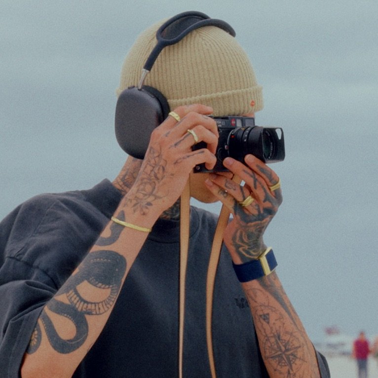 A smiling young woman in a pink blouse stands in an office setting, with soft lighting and a professional backdrop.