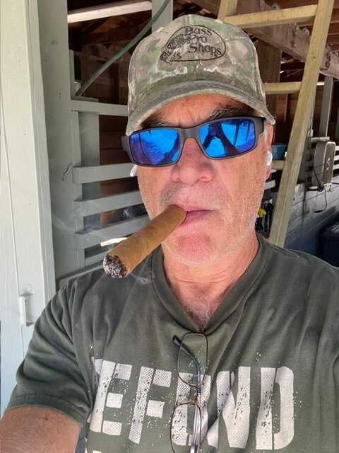 AGL Grass North owner Jerry smoking a cigar and wearing cool, blue sunglasses.