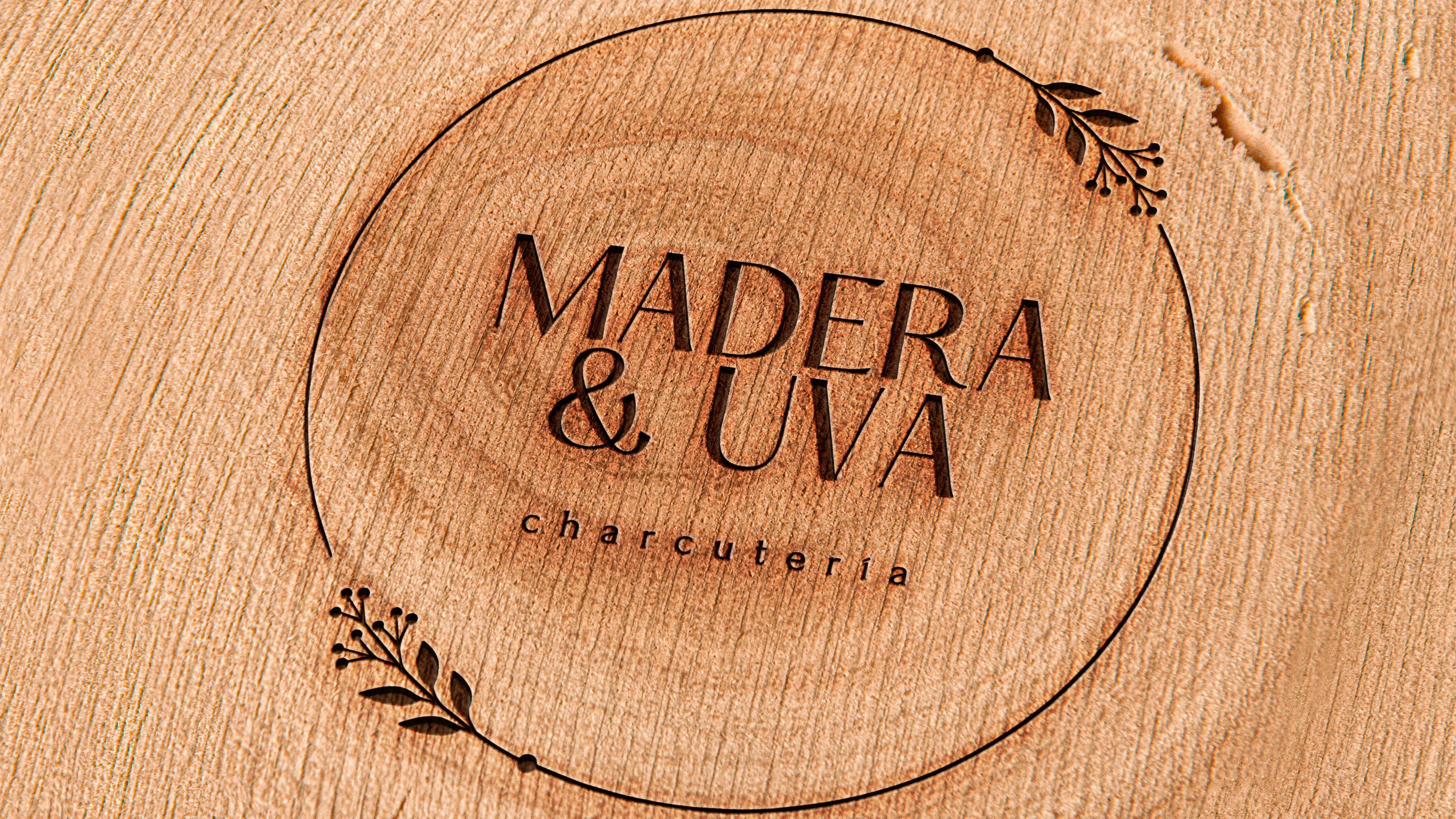 Logotipo de "Madera y Uva" grabado sobre superficie de madera