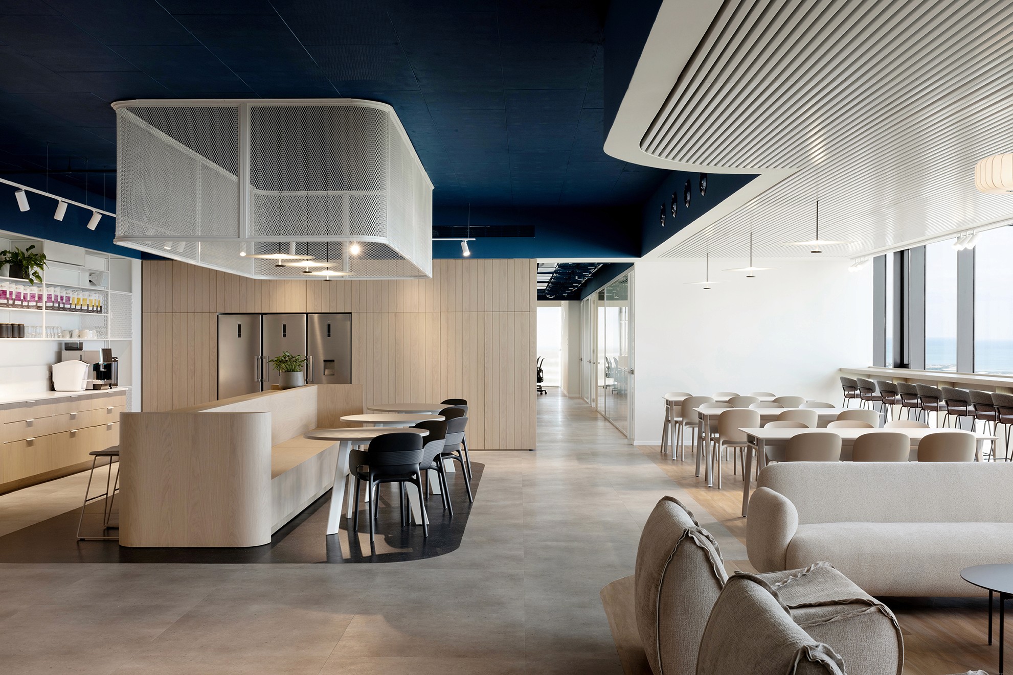 עיצוב קפיטריה מודרנית: אלמנט תקרה מרחף מרשת מתכת (Expanded Mesh) המדמה ממברנות סינון, מעל אי עבודה מרכזי