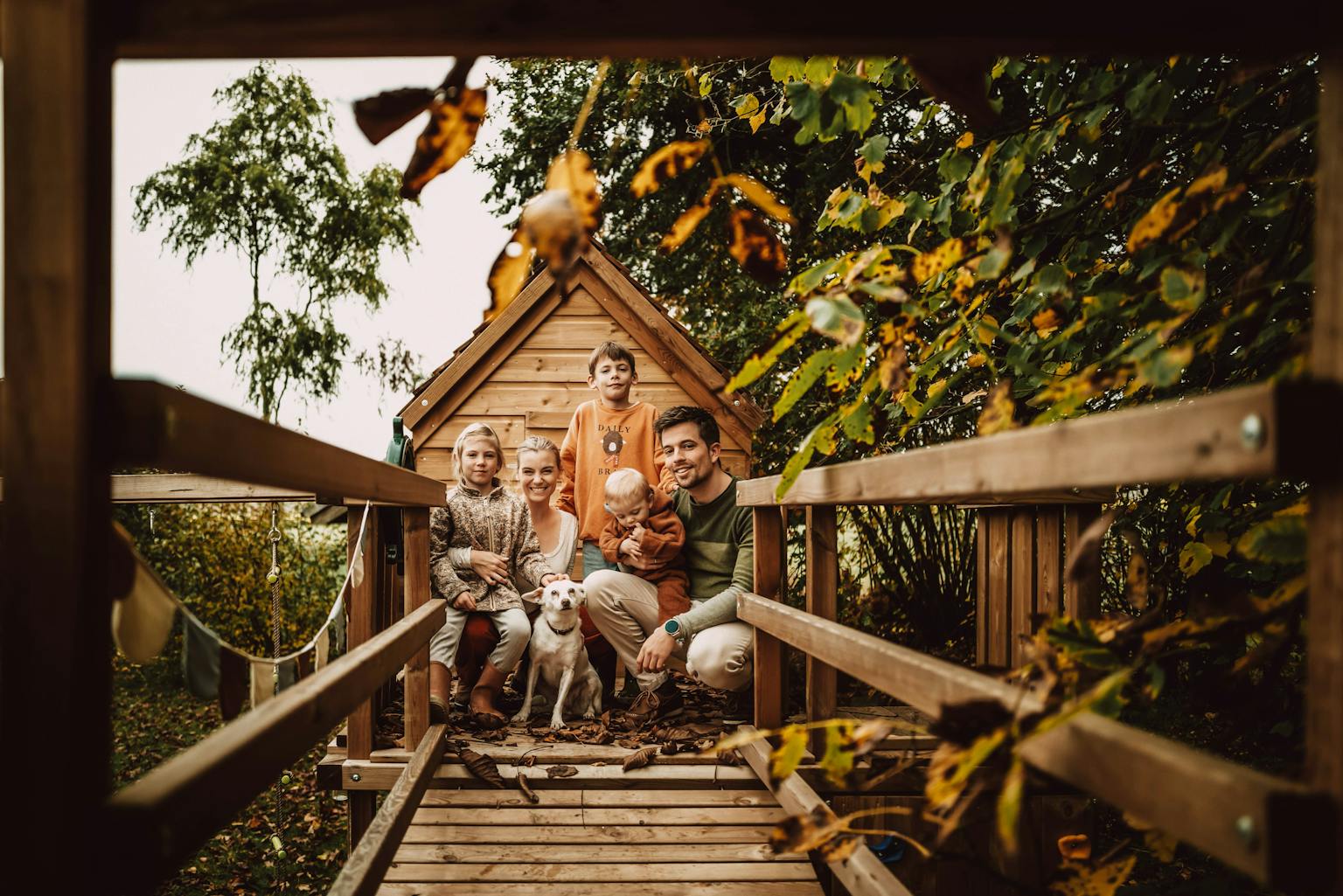 Een houten pad leidt naar een rustieke blokhut, omringd door bomen en natuur. Warme, uitnodigende sfeer.