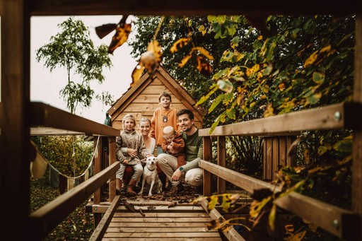 A wooden pathway leads to a rustic cabin, surrounded by trees and nature. Warm, inviting atmosphere.