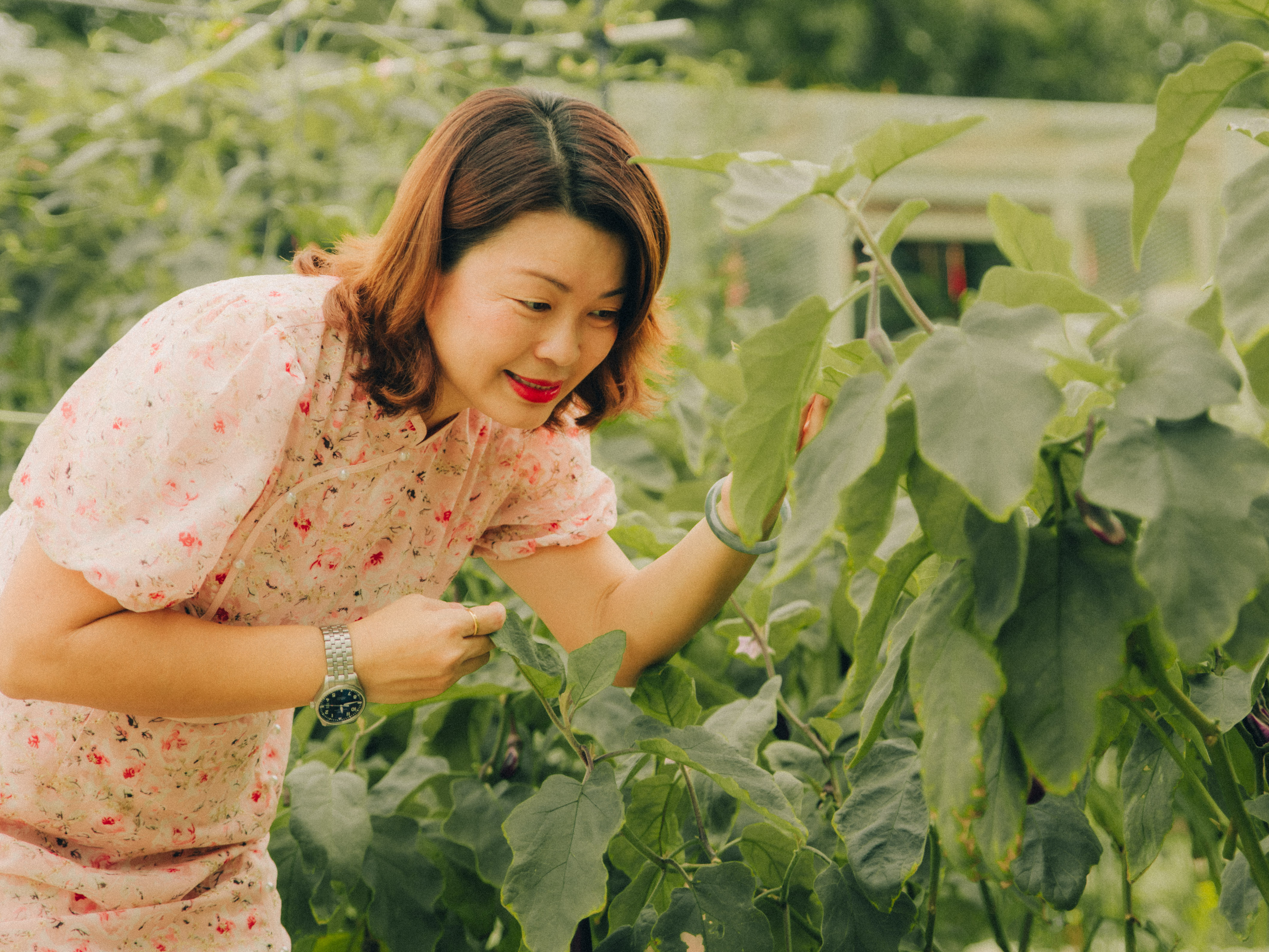 Elegant portrait of a woman amidst the greenery, wearing a modern cheongsam for Chinese New Year.