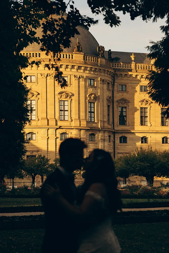 Brautpaar als Silhouette vor beleuchteten Barock Schloss bei Sonnenuntergang, aufgenommen von Hochzeitsfotografin Eva Sitko