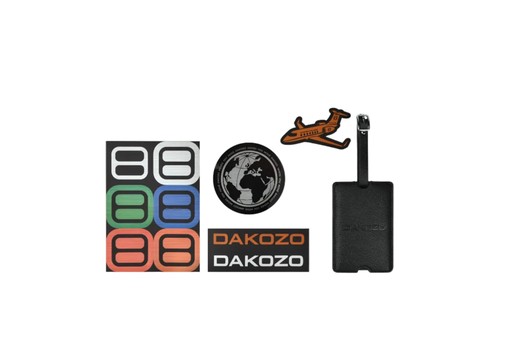 Collection of Dakozo products including a luggage tag, airplane model, and stickers on a white background.