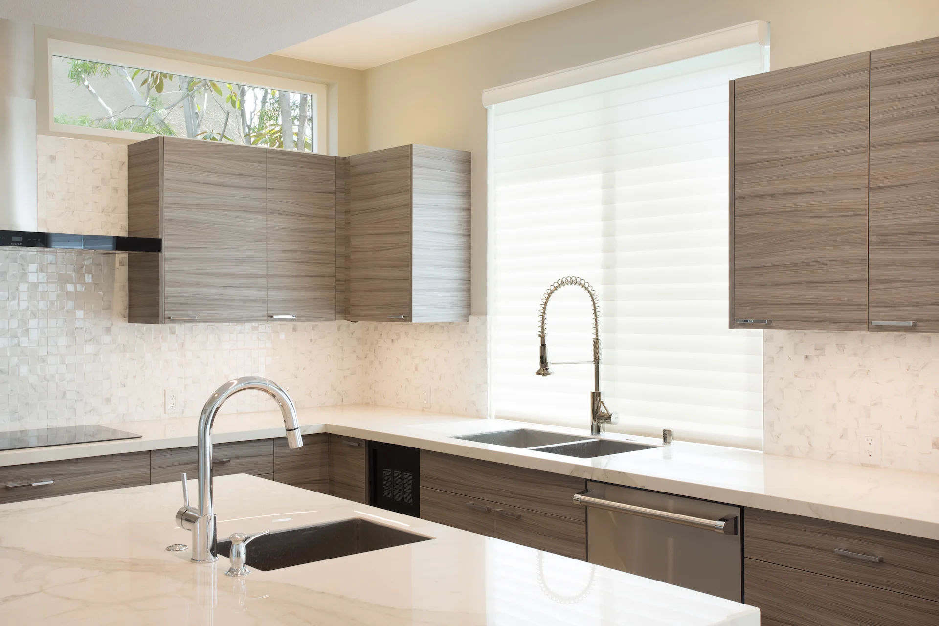 Closeup of the sink wall over the kitchen island, displaying the elegant design and modern fixtures in this Newport Beach home.