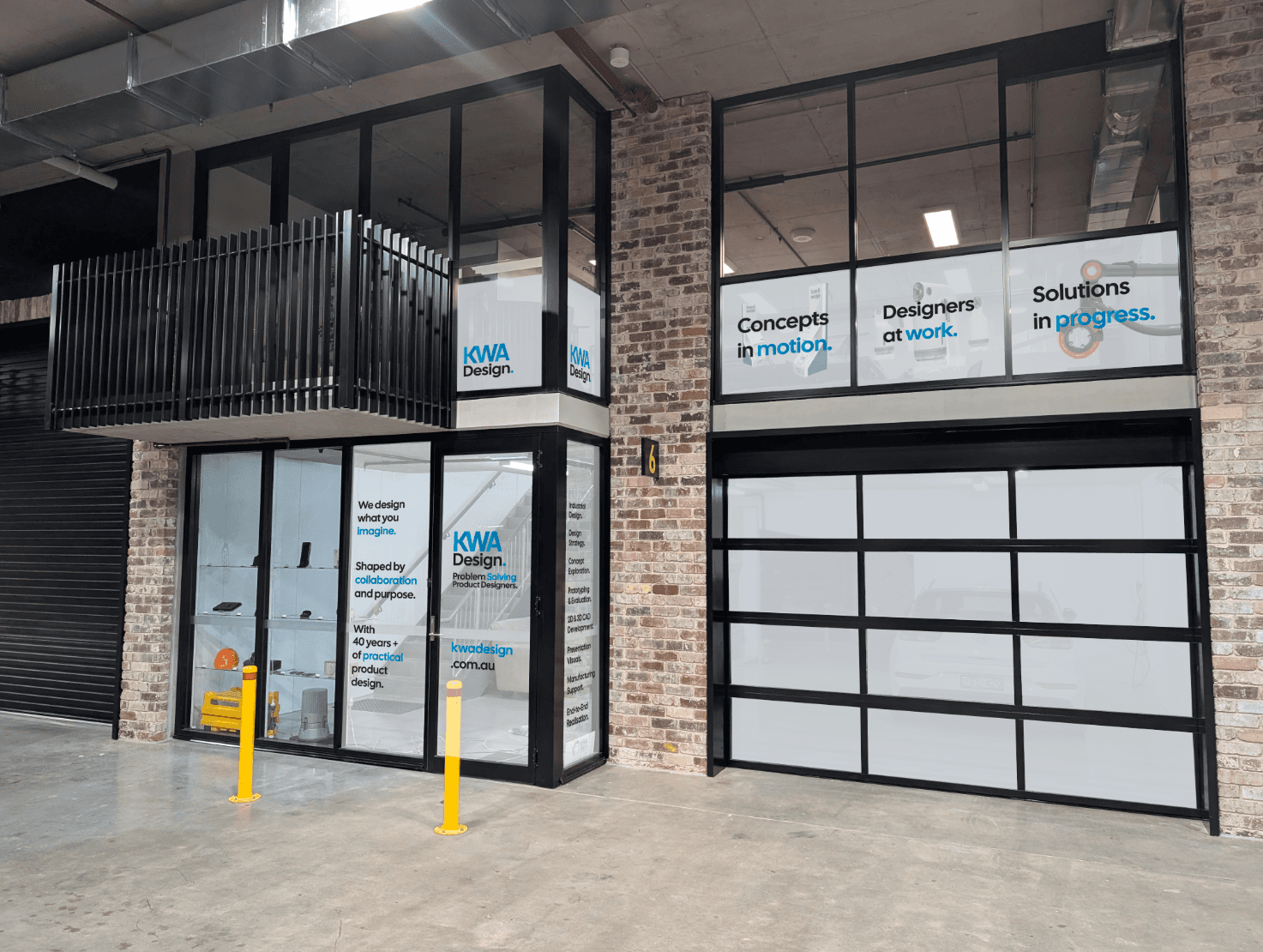 Exterior view of KWA Design studio with branded signage on glass panels, showcasing product design services, slogans, and display shelves inside the entrance