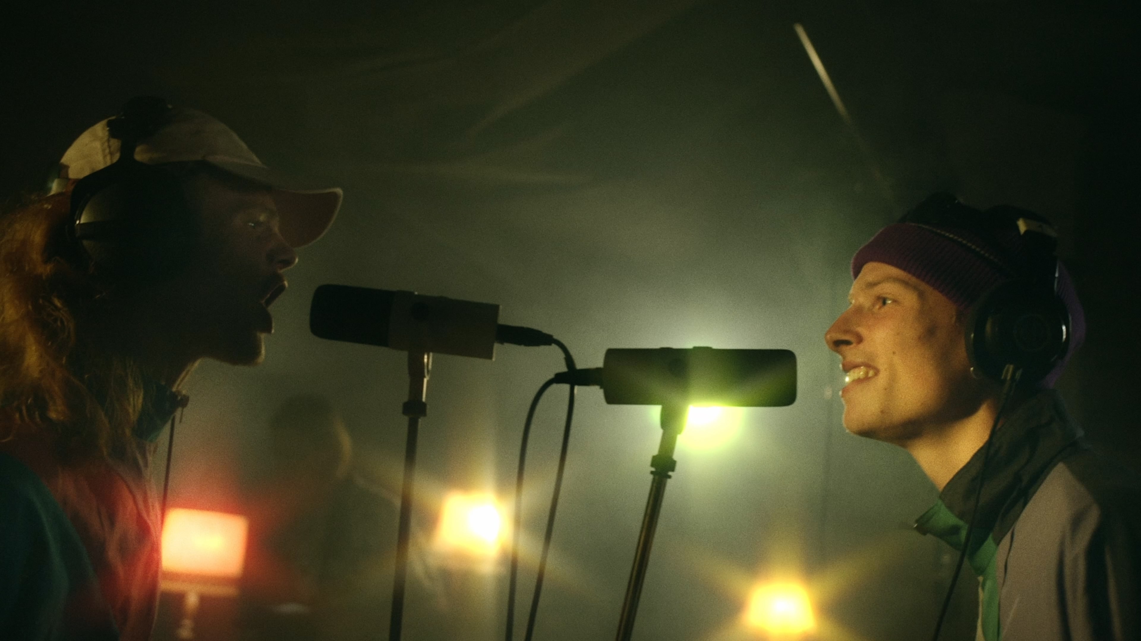 2 men are singing in mics