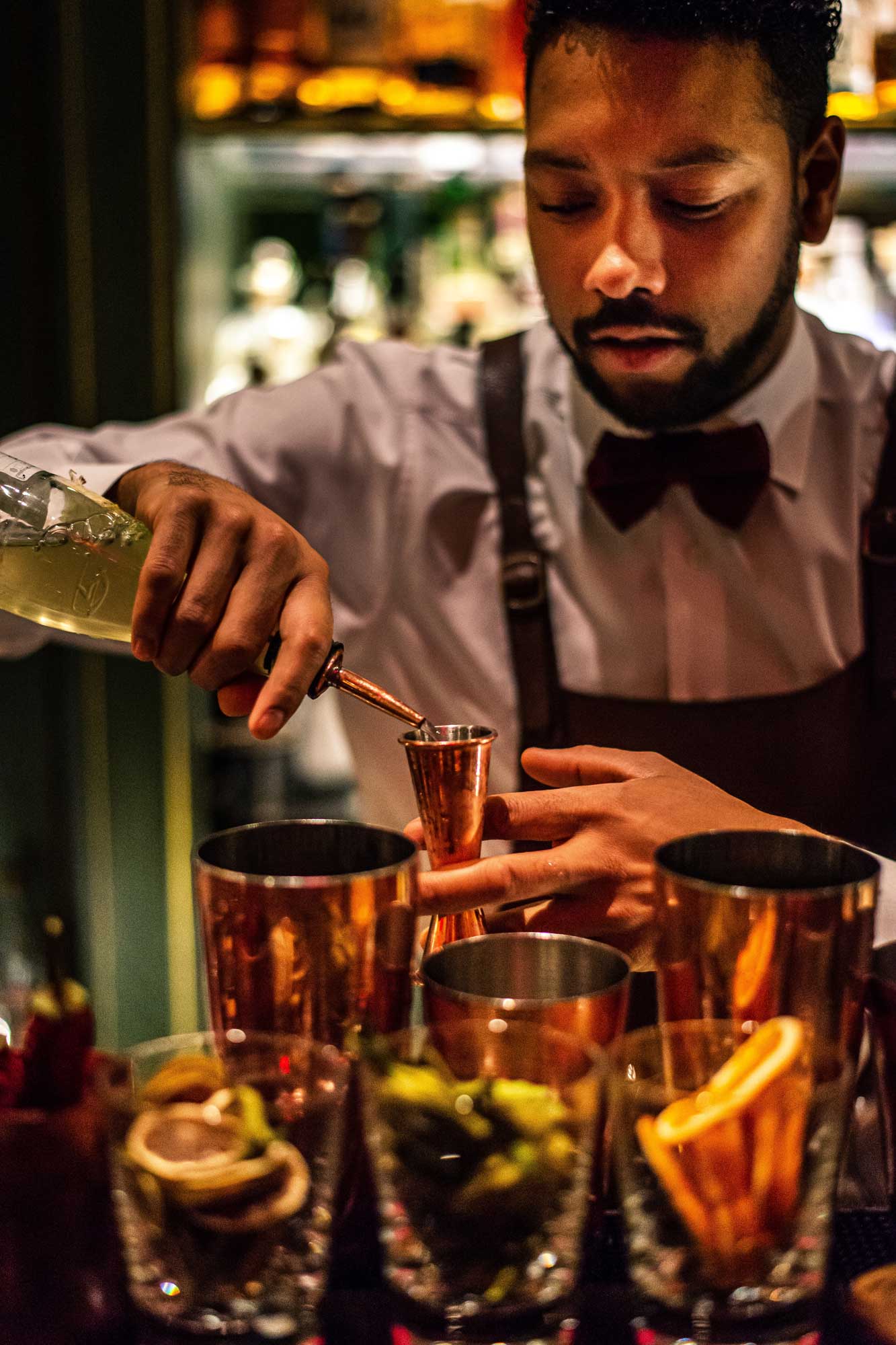 Bartender pouring cocktails into copper cups