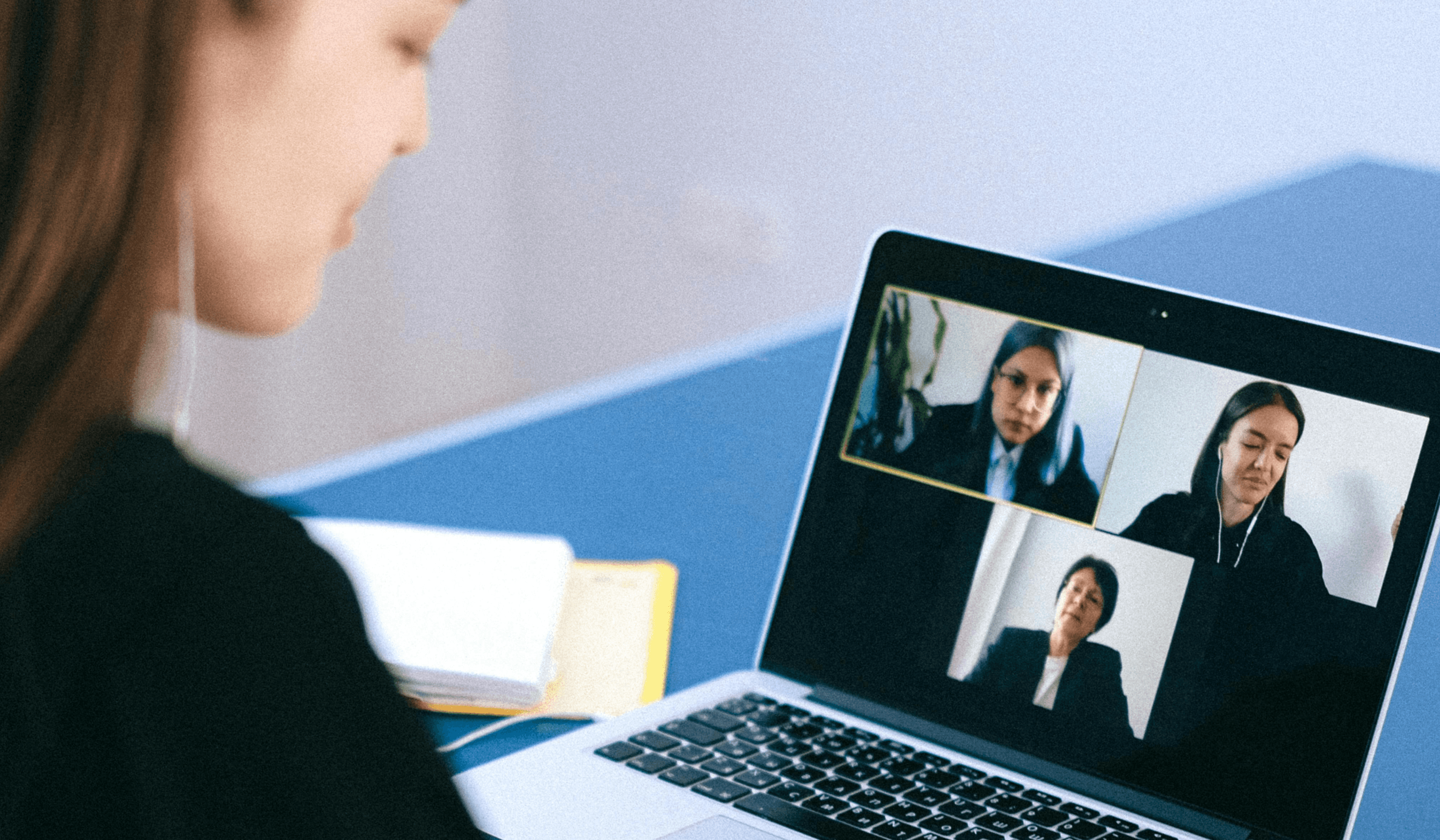 Frau sitzt vor einem Computer und nimmt an einem Webinar teil.