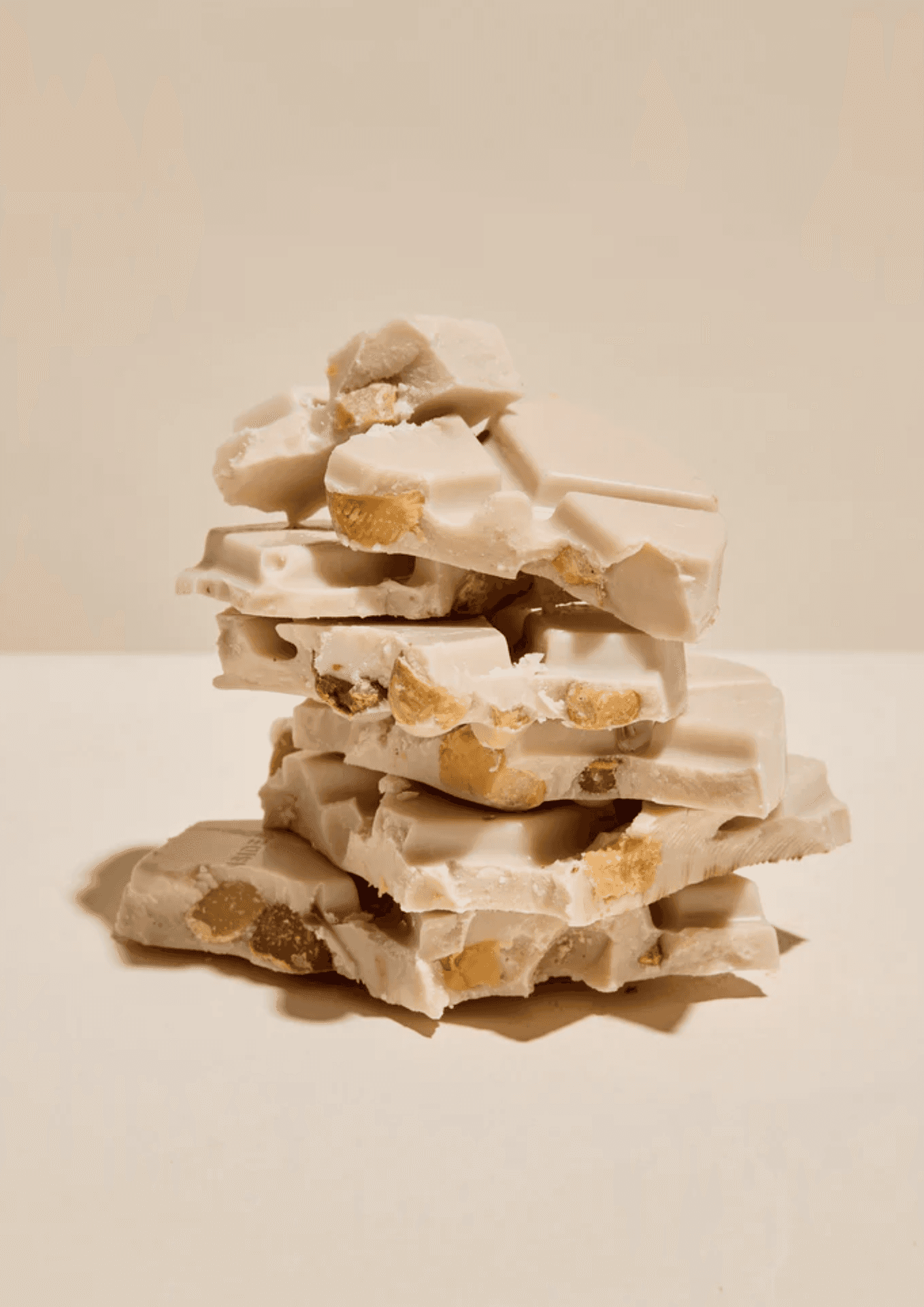 A stack of broken white chocolate dotted with nuts