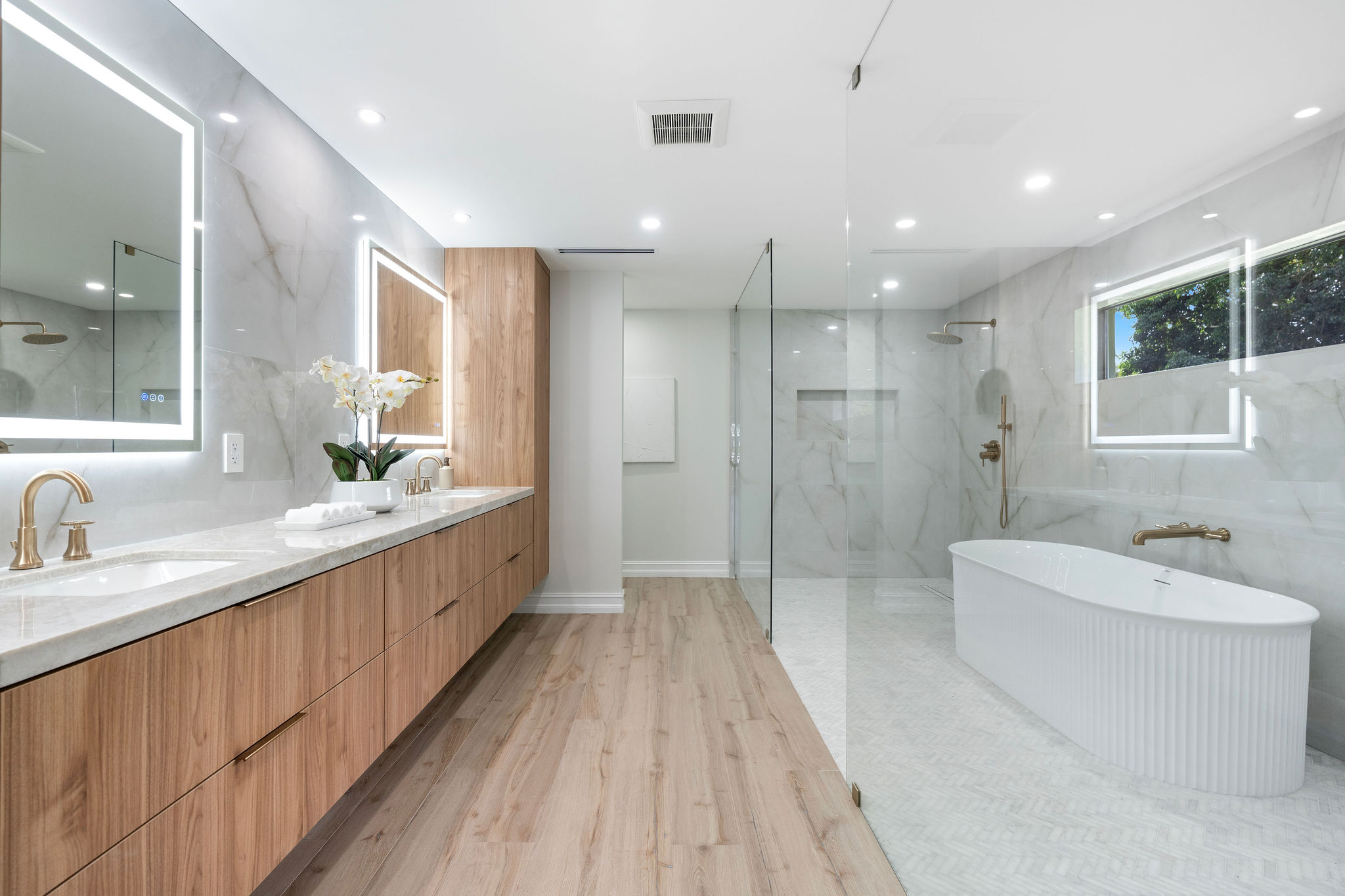 Modern bathroom with double vanity, freestanding tub, and glass shower.