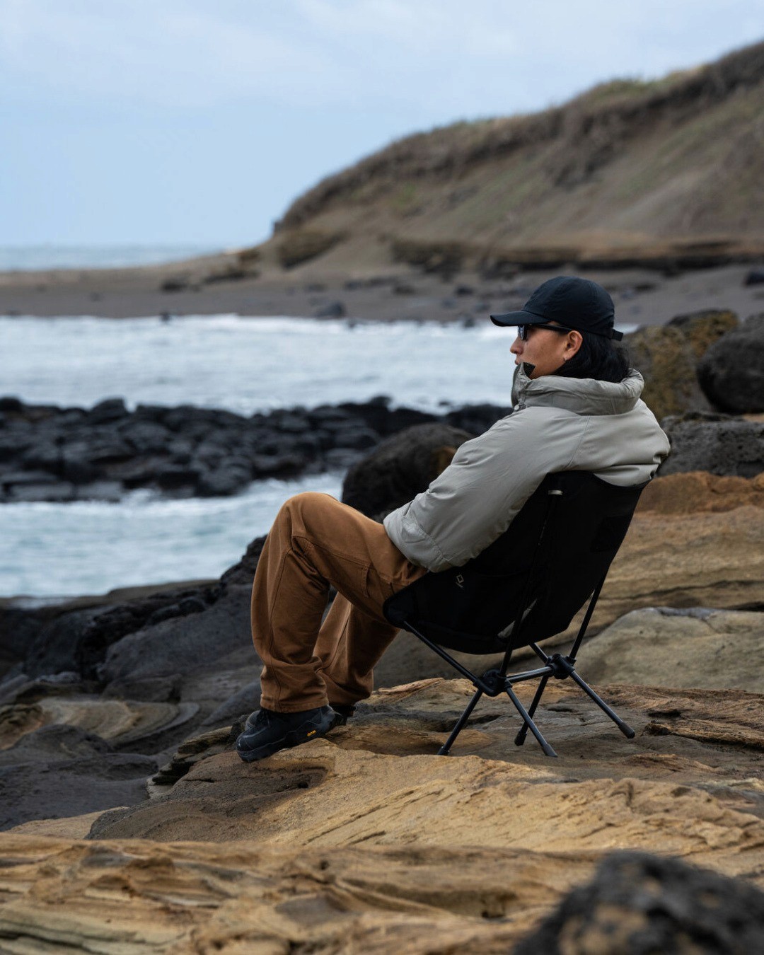 Un homme contemple la mer en hiver sur une chaisepliante de camping Helinox