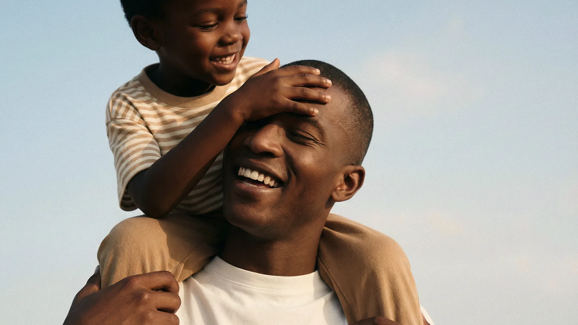 Smiling father carrying his young son on his shoulders, representing vitality, active living, and the pursuit of lifelong healthspan.