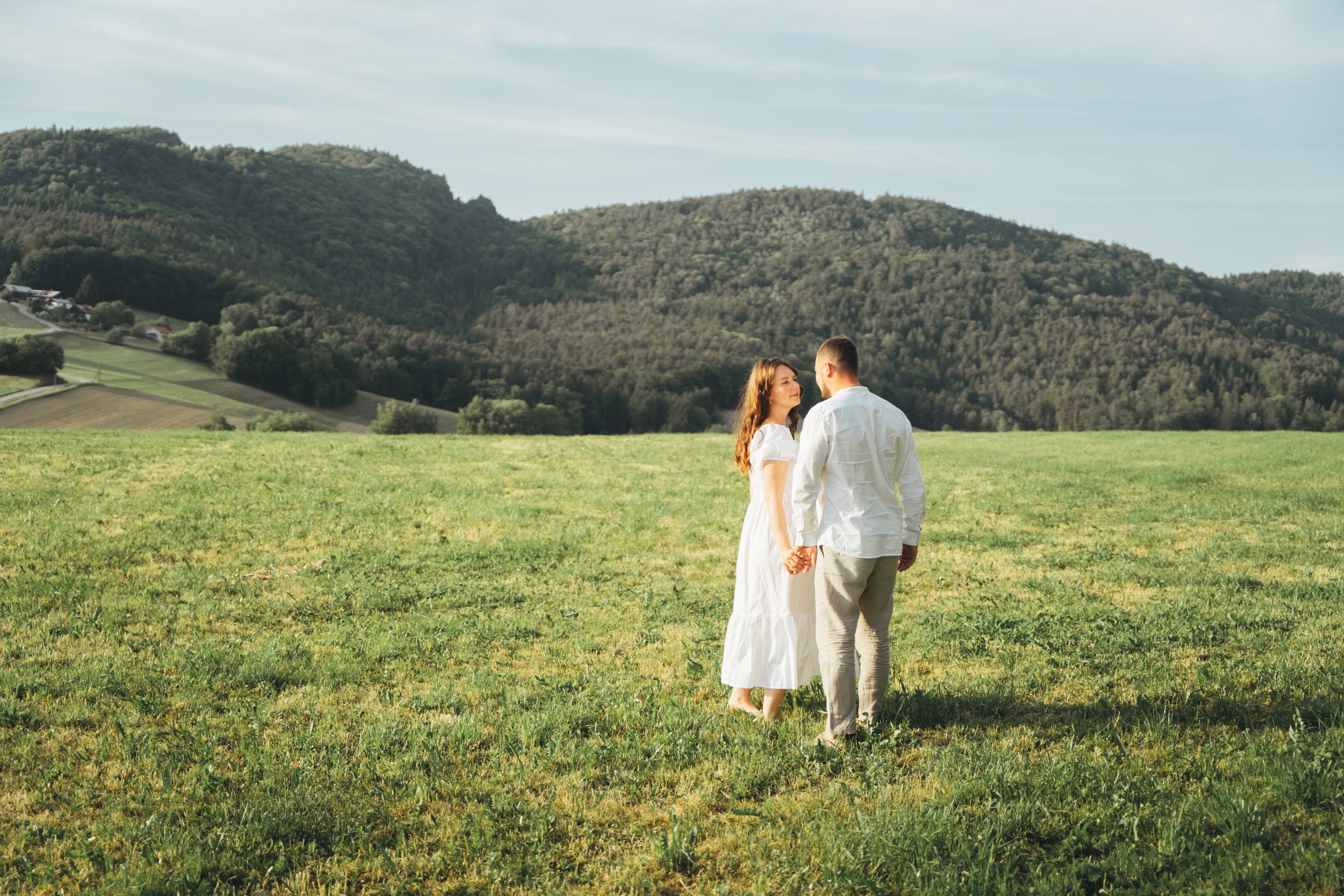 Schwangerschafts Fotoshooting in Bogen – Paar steht gemeinsam auf einer Wiese bei natürlicher Fotografie.