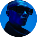 A person with short hair wearing large rectangular sunglasses, illuminated by blue lighting, conveys a futuristic, stylish, and mysterious tone.