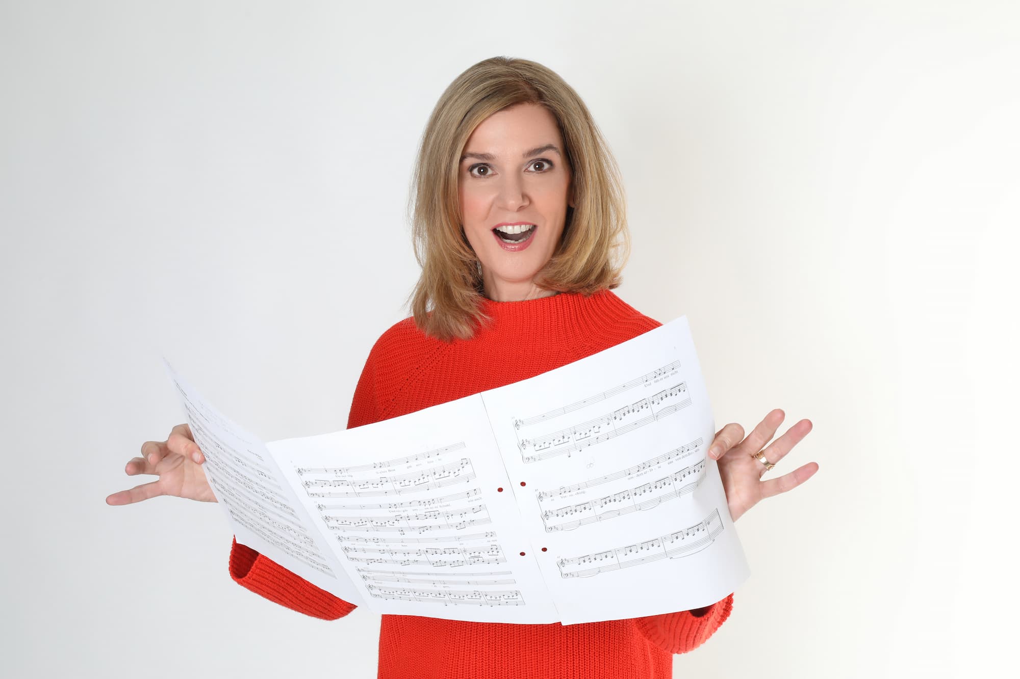 Vocal Coach Danielle Zuber hält überrascht Notenblätter in die Kamera – Gesangsunterricht bei Singers Evolution