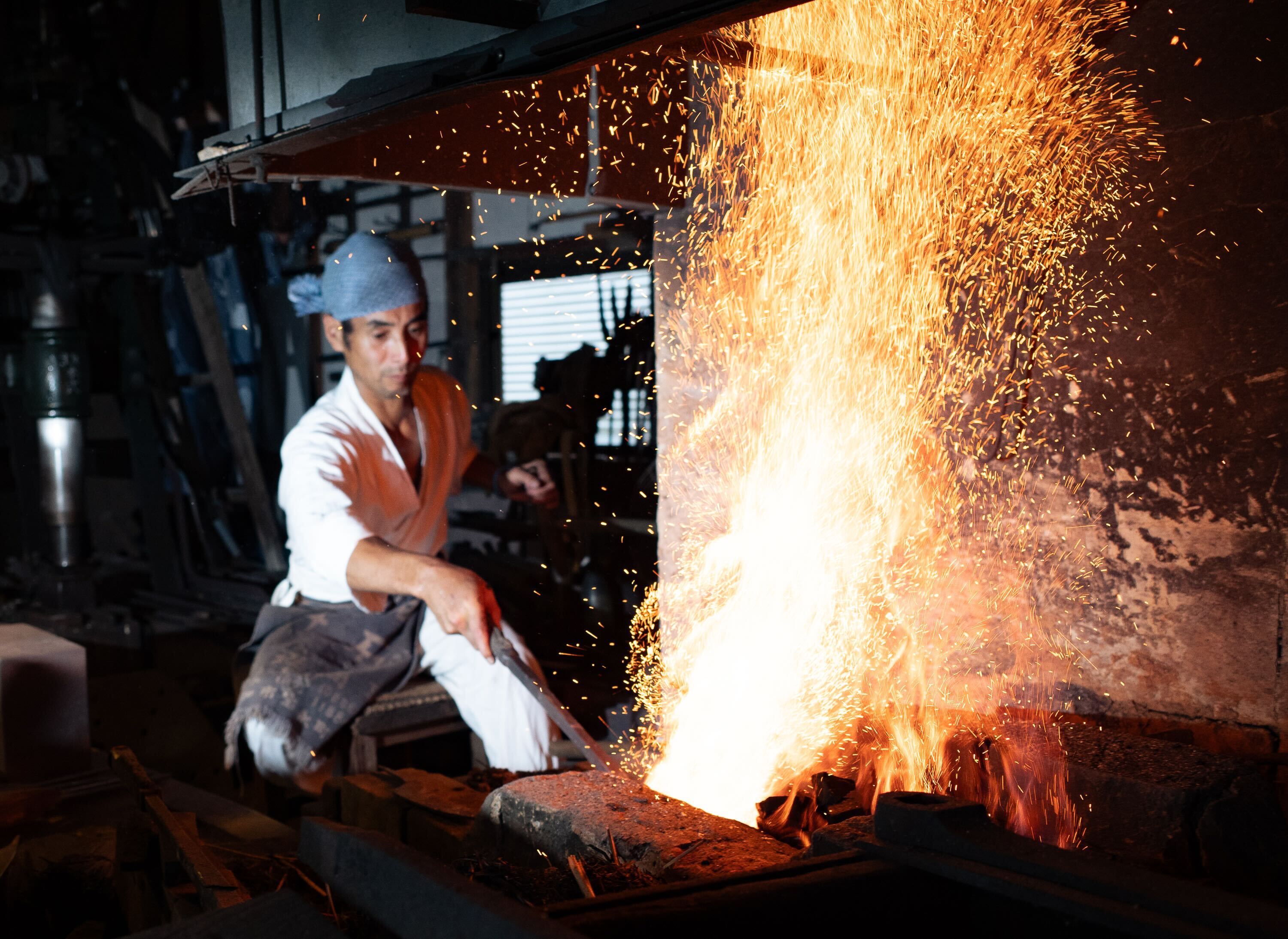 Swordsmiths hammering iron in a team