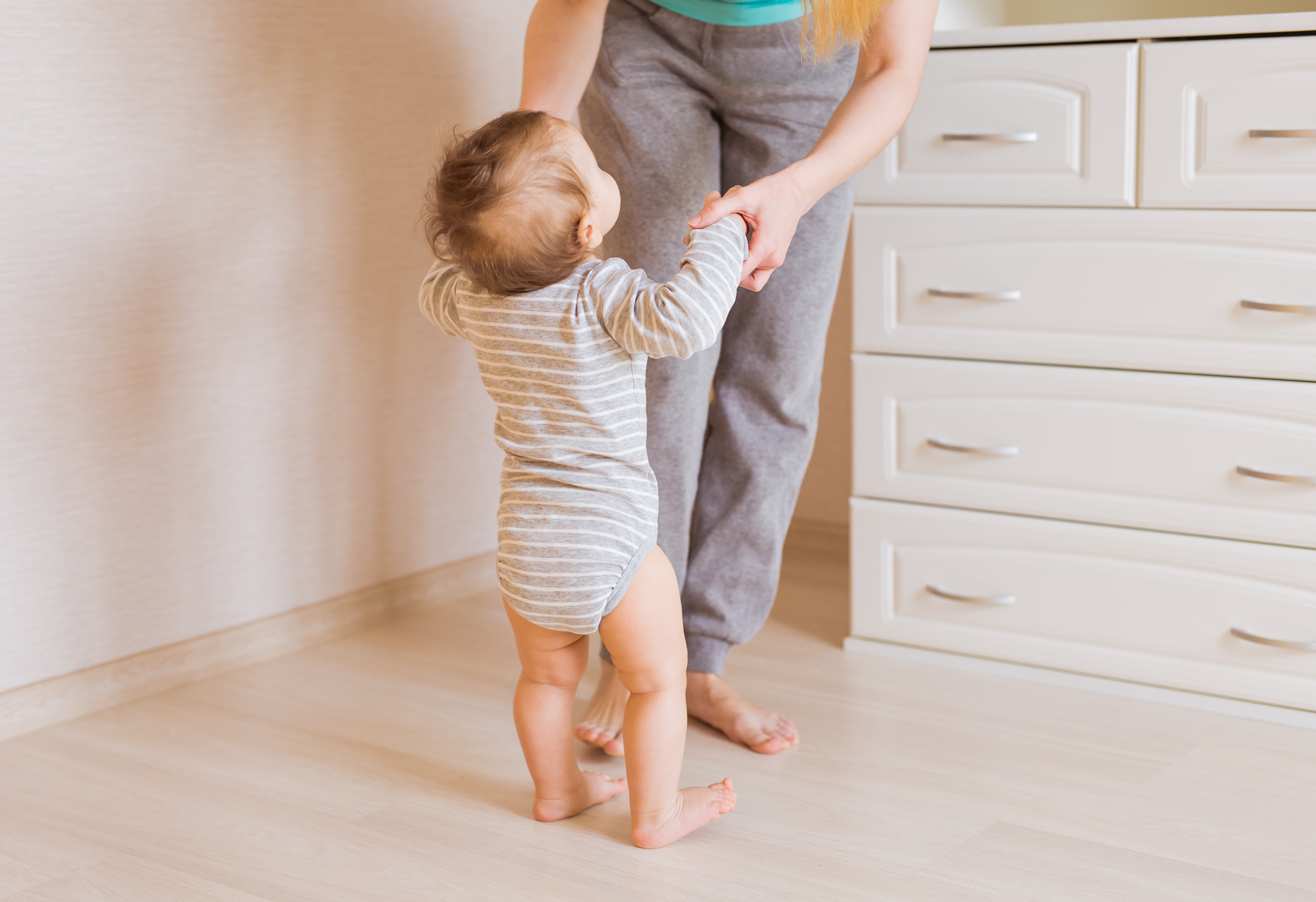 A toddler takes their first steps with a parent’s support on LUXO’s light wood-look hybrid flooring, highlighting its safe, slip-resistant, and child-friendly surface. Designed for Brisbane and Australian homes, the durable flooring provides comfort underfoot, easy cleaning, and peace of mind for growing families.