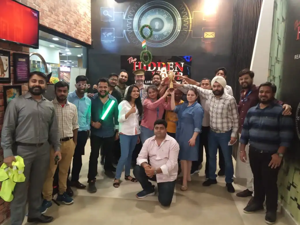 Company team celebrating a win with a trophy at Hidden Hour’s escape room