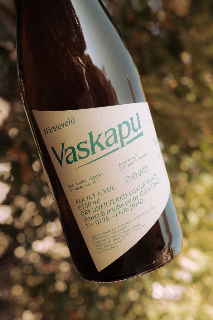Vaskapu Hárslevelű natural white wine bottle in warm sunlight, with typographic label designed by Marcell Kazsik — highlighting the handcrafted elegance of Hungarian low-intervention wines.