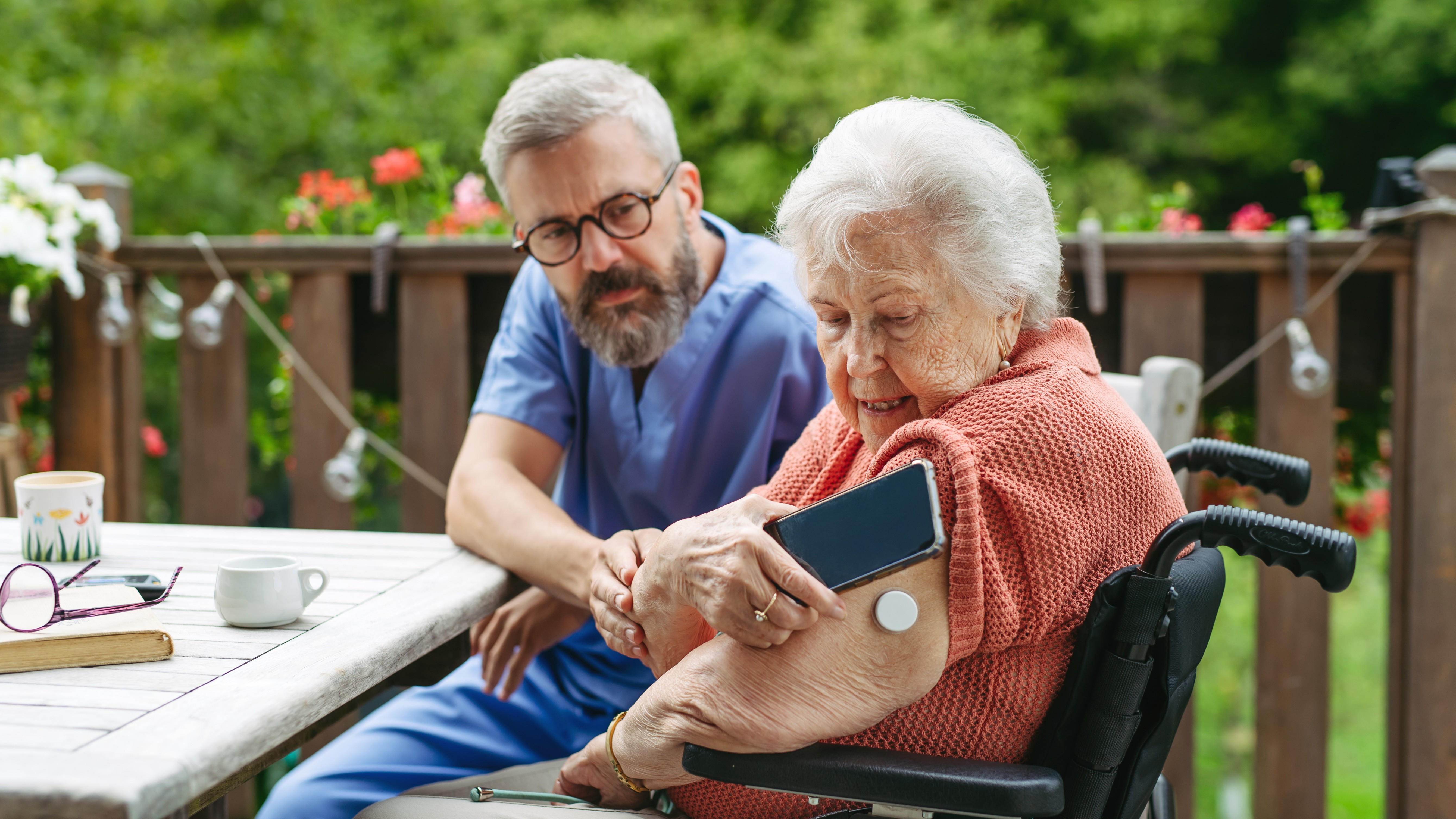 An elder using a smartphone to detect a glucose meter on their arm.