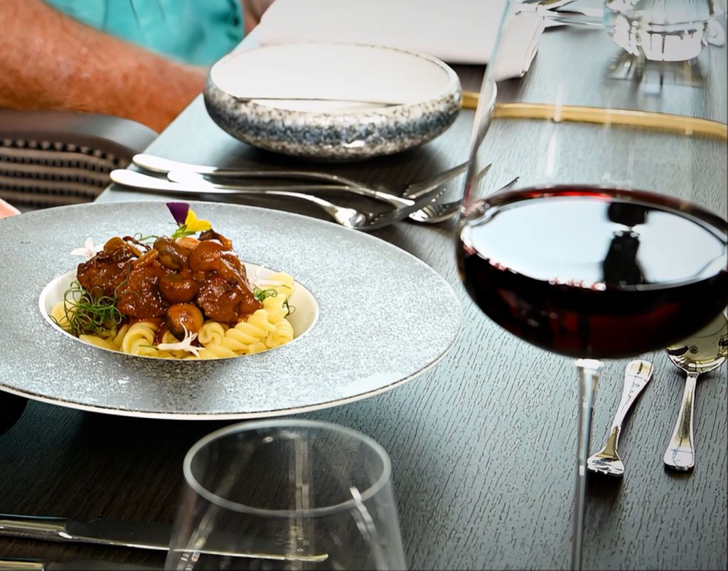 Fine dining table setting with plated food, wine glasses, and elegant tableware