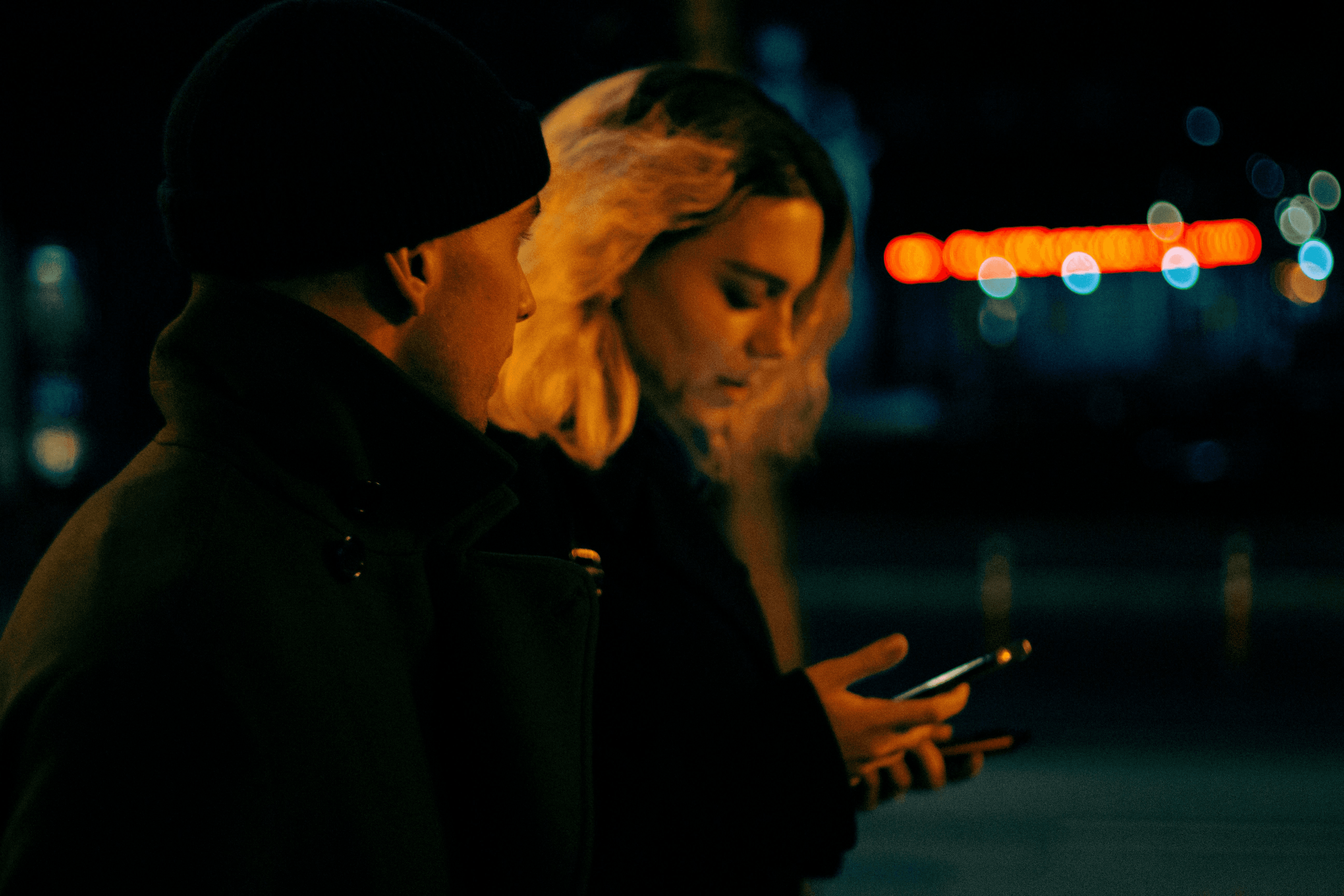 woman holding a phone and man looking at the phone. both are smiling