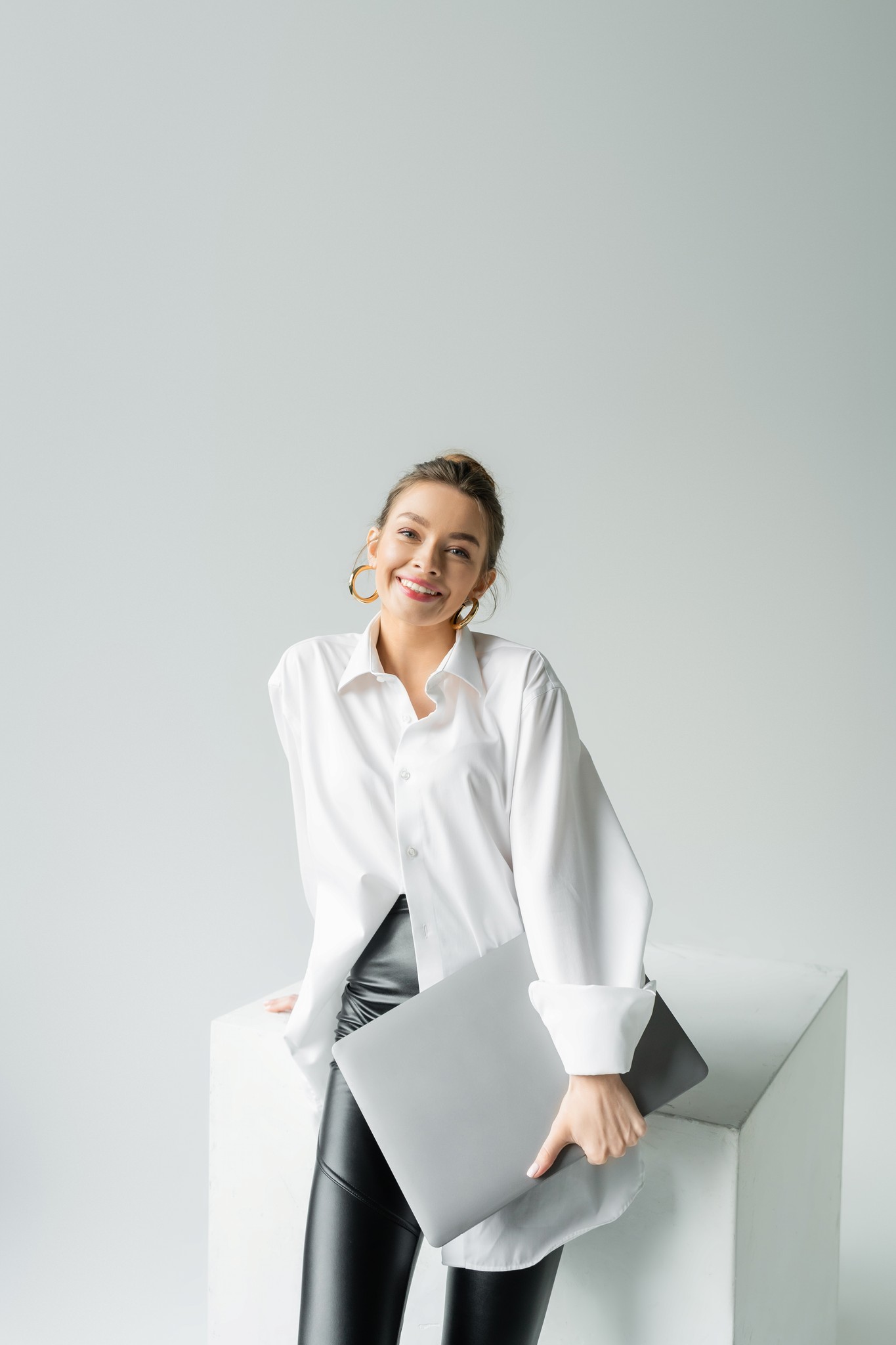 Professional holding a laptop in a light studio