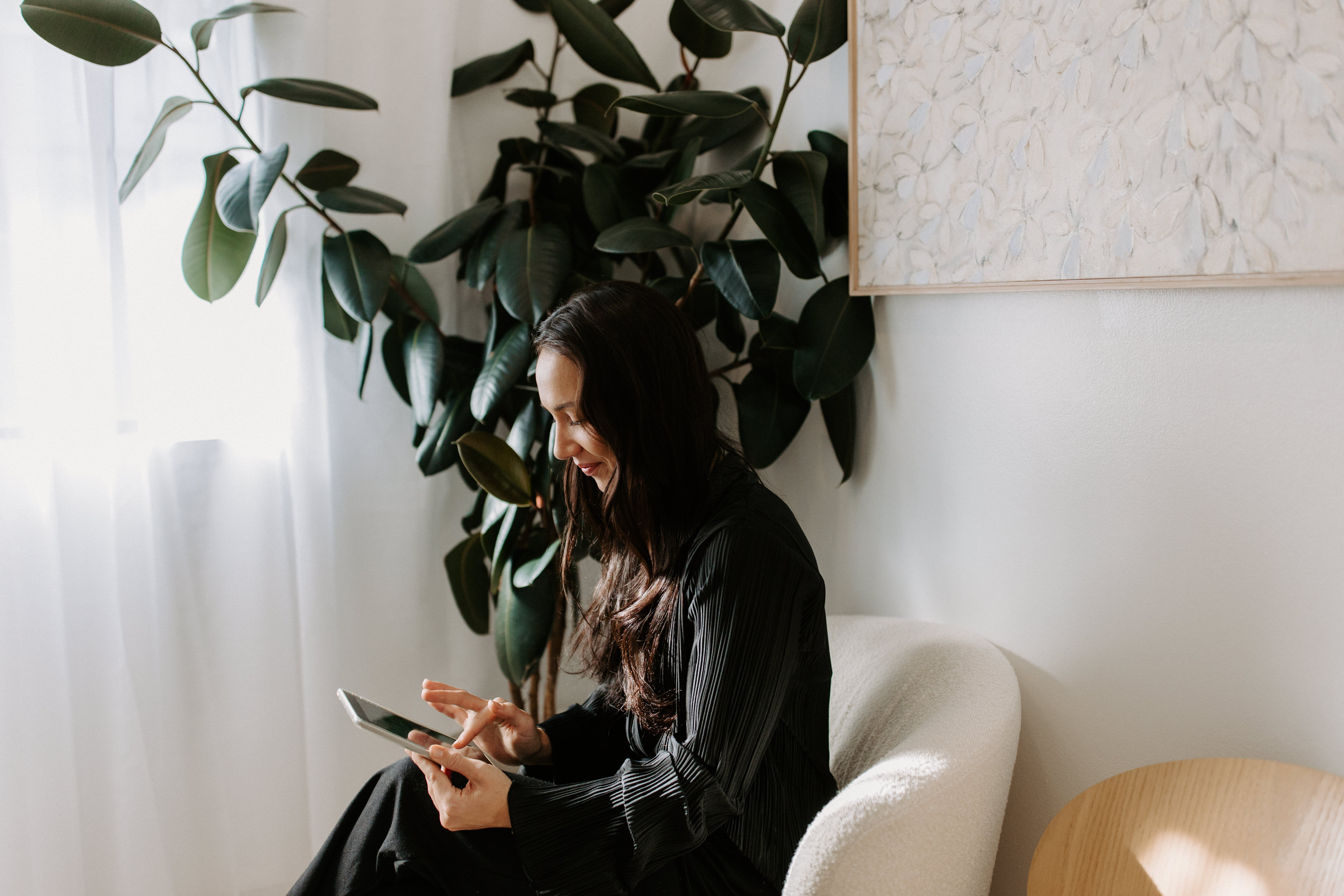 A female patient sitting in the reception area of Surry Hills Dental Centre, using an iPad to fill in her details