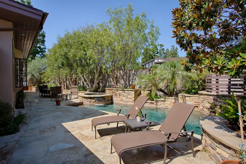 Hardscaped outdoor pool lounge chairs beside the pool.from the Big Canyon Remodel project. Photo by Chris Darnall.