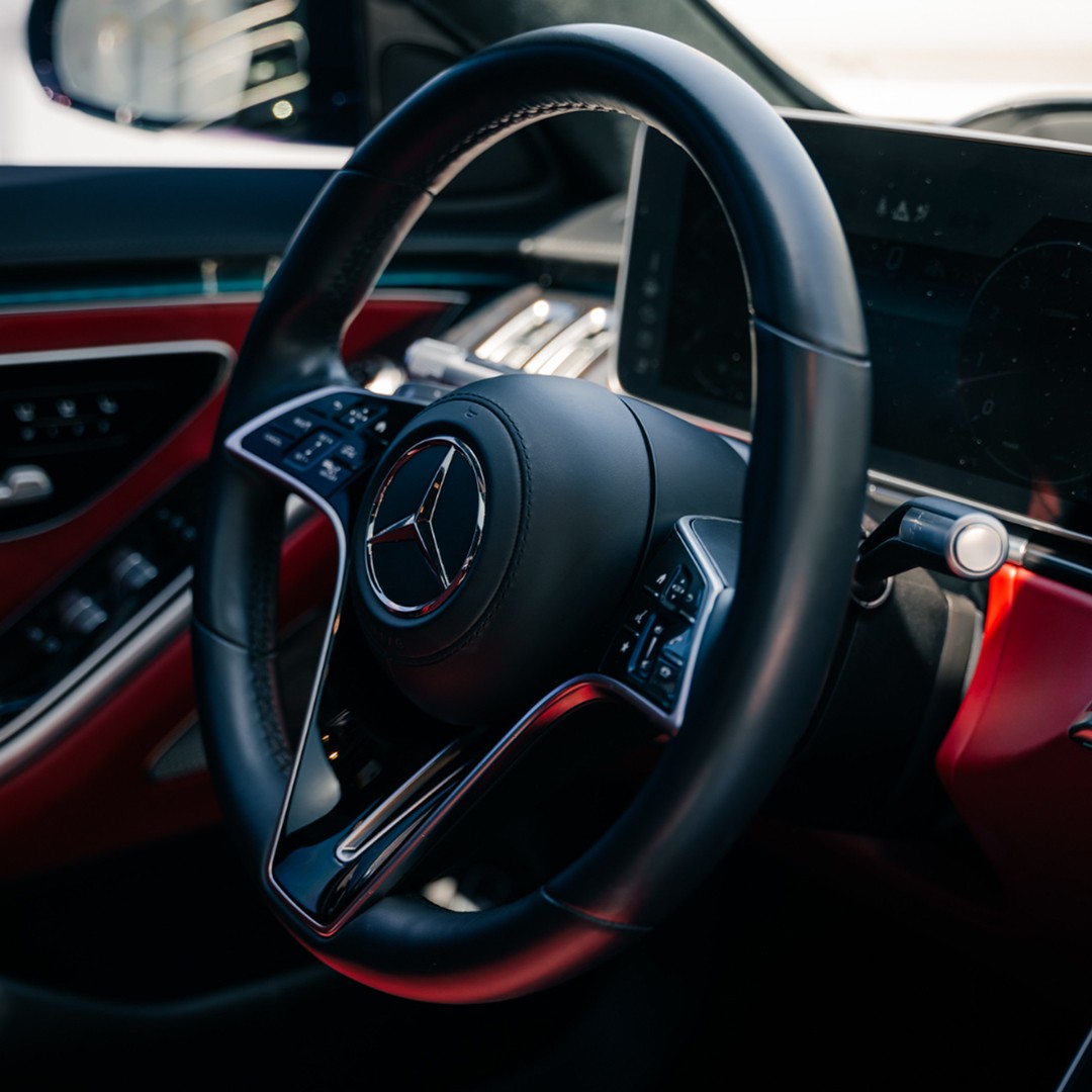 Driver's cockpit of the Mercedes-Benz S 580, featuring a vibrant red leather interior and advanced digital displays.